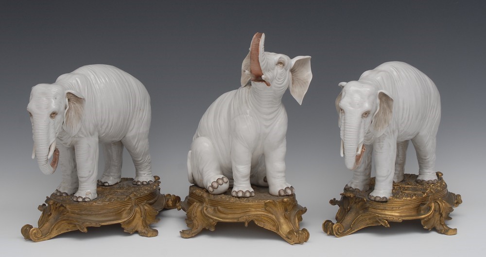 A garniture of three substantial 19th century ormolu mounted Continental porcelain models of elephants