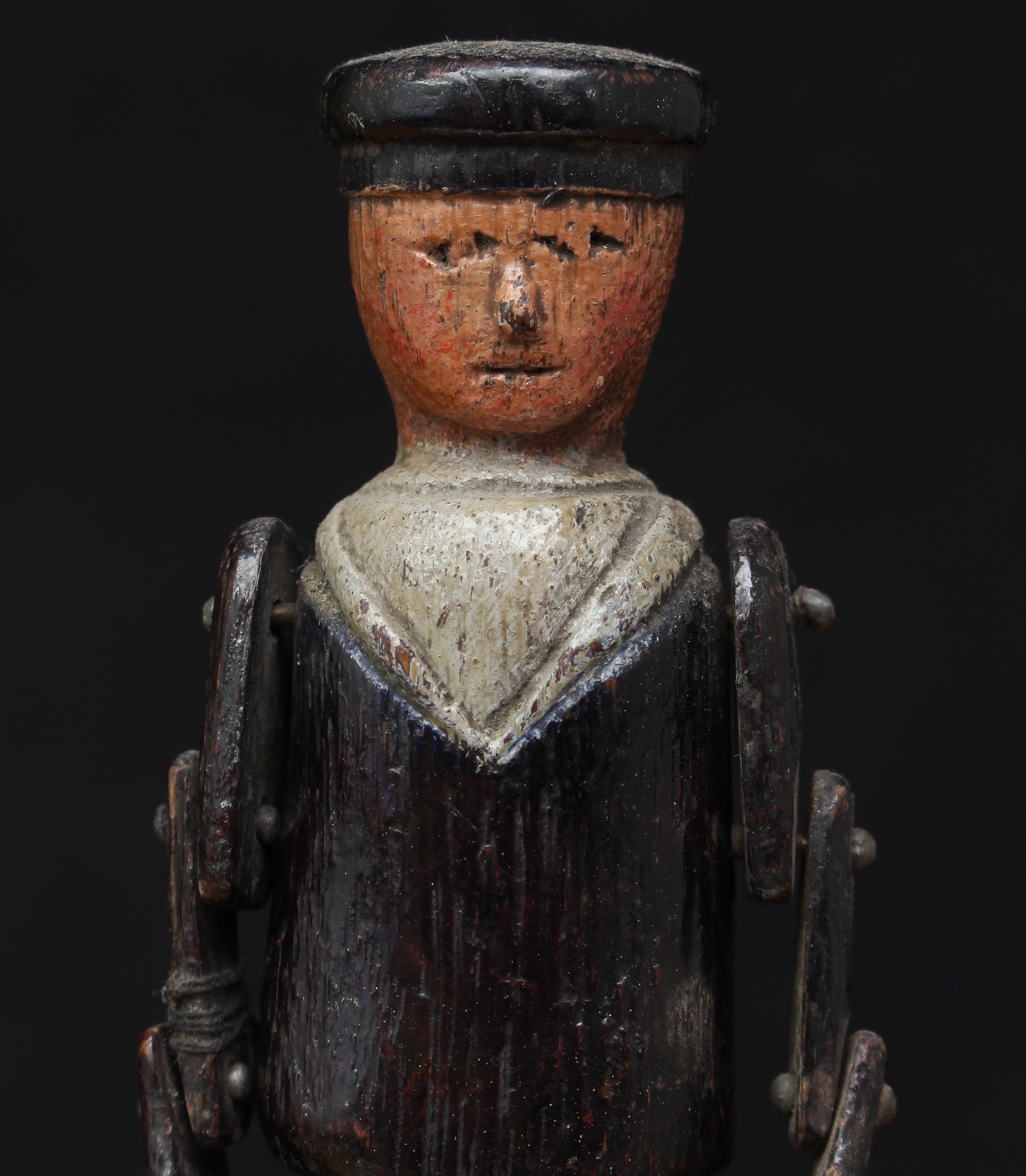 Folk Art and Maritime Interest - a late 19th/early 20th century painted wooden sailor doll, realistically carved throughout, wearing a navy blue sailors uniform, articulated limbs with fork type hands, probably American, 21cm high, displayed on a wooden display stand