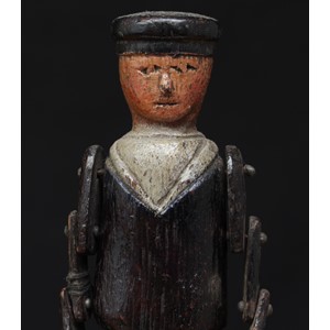 Folk Art and Maritime Interest - a late 19th/early 20th century painted wooden sailor doll, realistically carved throughout, wearing a navy blue sailors uniform, articulated limbs with fork type hands, probably American, 21cm high, displayed on a wooden display stand