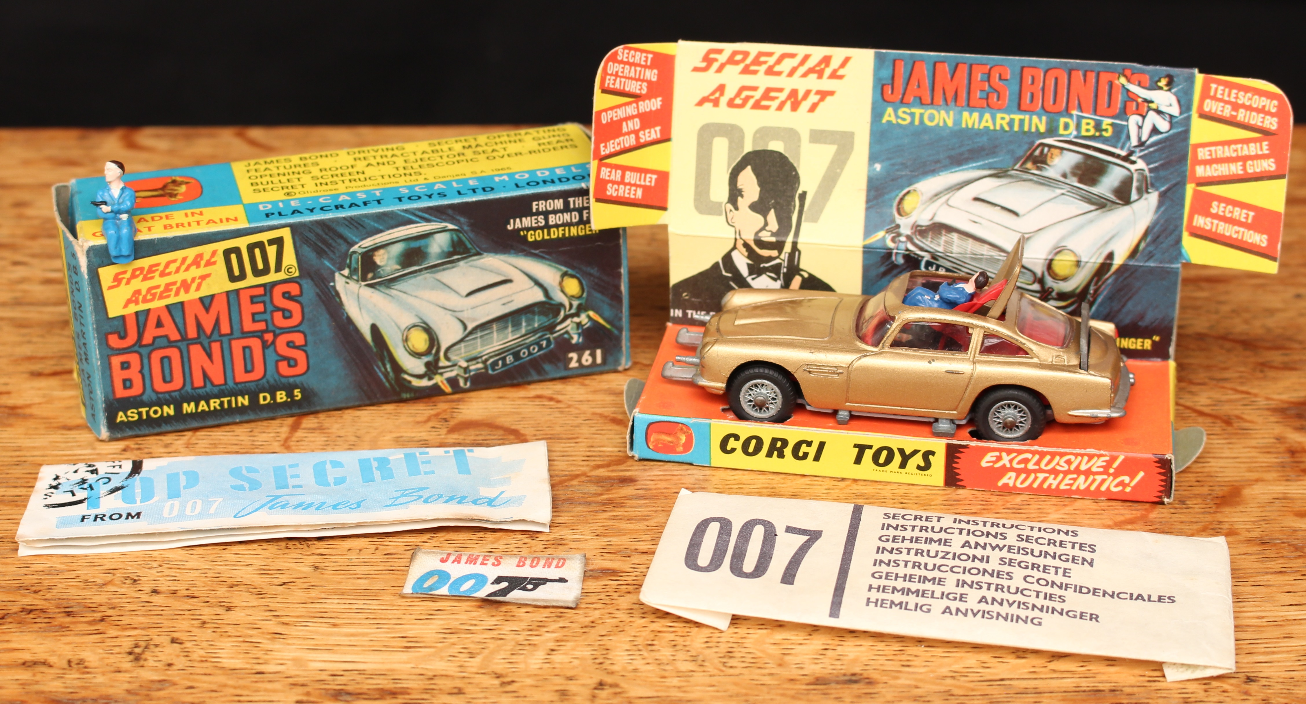 Corgi Toys 261 Special Agent 007 James Bond's Aston Martin D.B.5. from the James Bond film "Goldfinger", gold body with red interior, wire spoke wheels, James Bond and seated plastic bandit figure to interior, boxed with inner cardboard pictorial display stand, 'secret instructions' with packet, spare plastic bandit figure and 007 badge