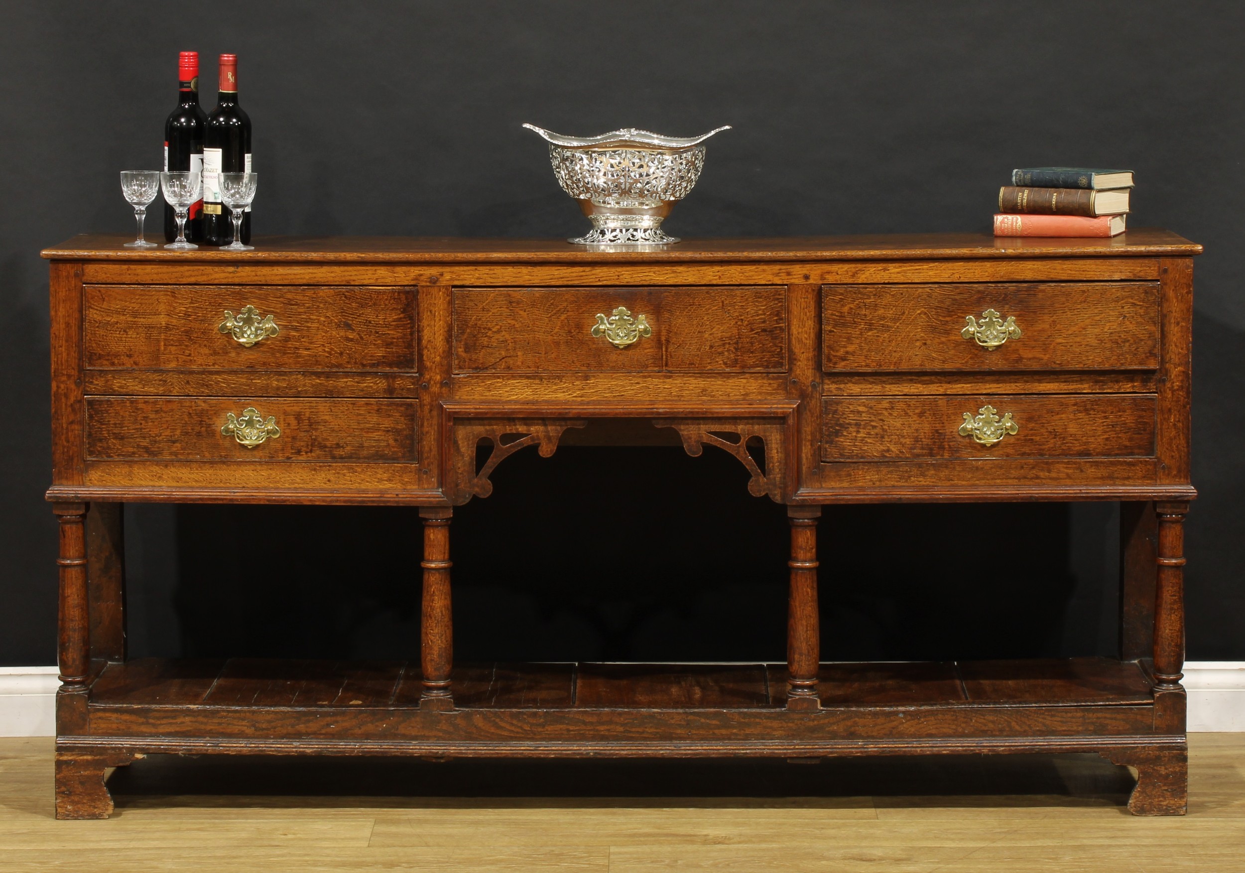 A George III and later oak low pot board dresser, slightly oversailing top above an arrangement of five drawers, turned foresupports, stile feet applied to the front with brackets, 88.5cm high, 177.5cm wide, 40cm deep, elements c.1800 with later renovations