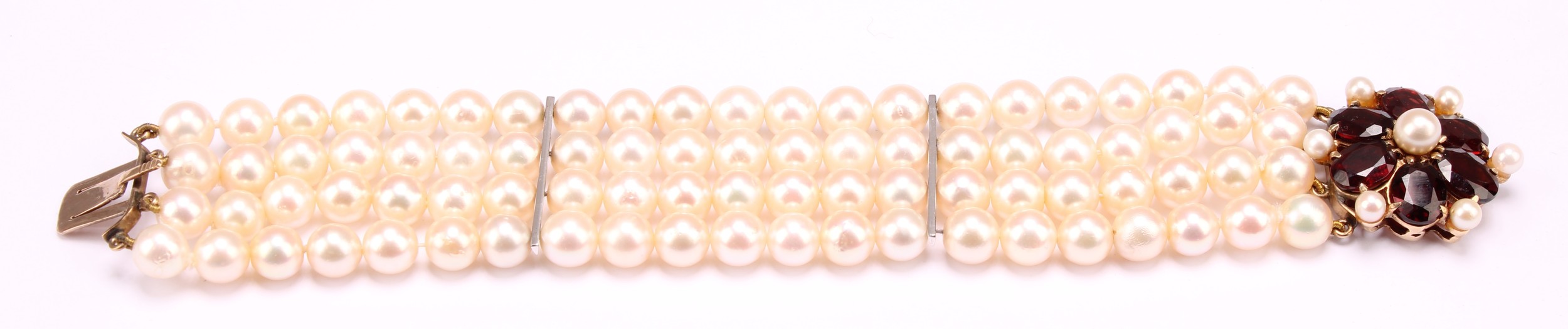 A garnet and cream cultured pearl bracelet with pink overtones, four strand with two bar dividers with 9ct gold flower design clasp