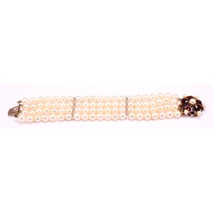 A garnet and cream cultured pearl bracelet with pink overtones, four strand with two bar dividers with 9ct gold flower design clasp