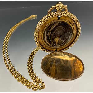 A Victorian yellow metal mourning locket, engine turned and floral decoration, the interior with hair and wire work panel, unmarked mount