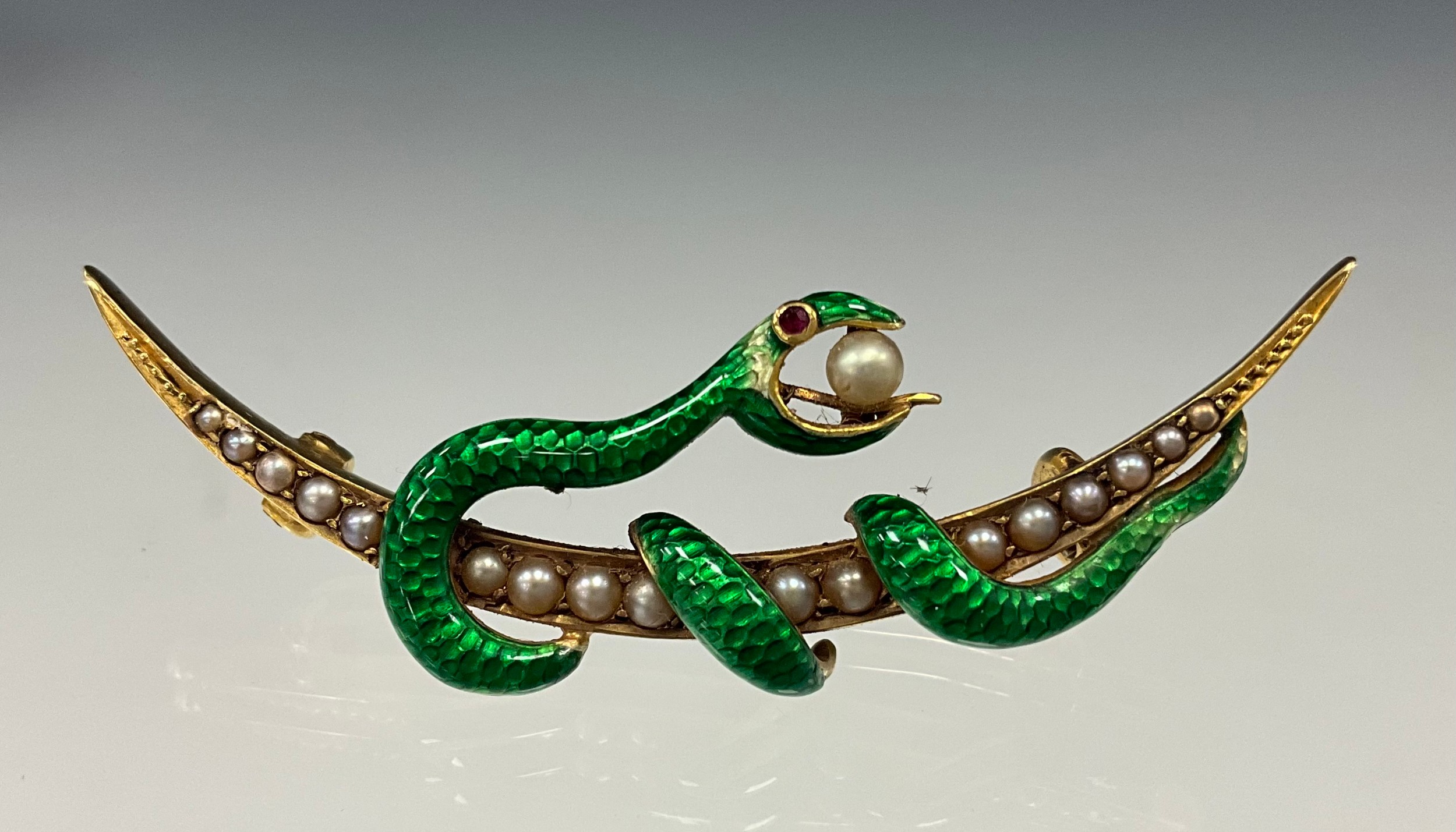 An early 20th century green enamel seed pearls serpent and crescent brooch