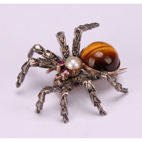 A white and yellow gold coloured metal novelty brooch, as a spider, set with diamonds, rubies, a split pearl and a tiger’s eye cabochon