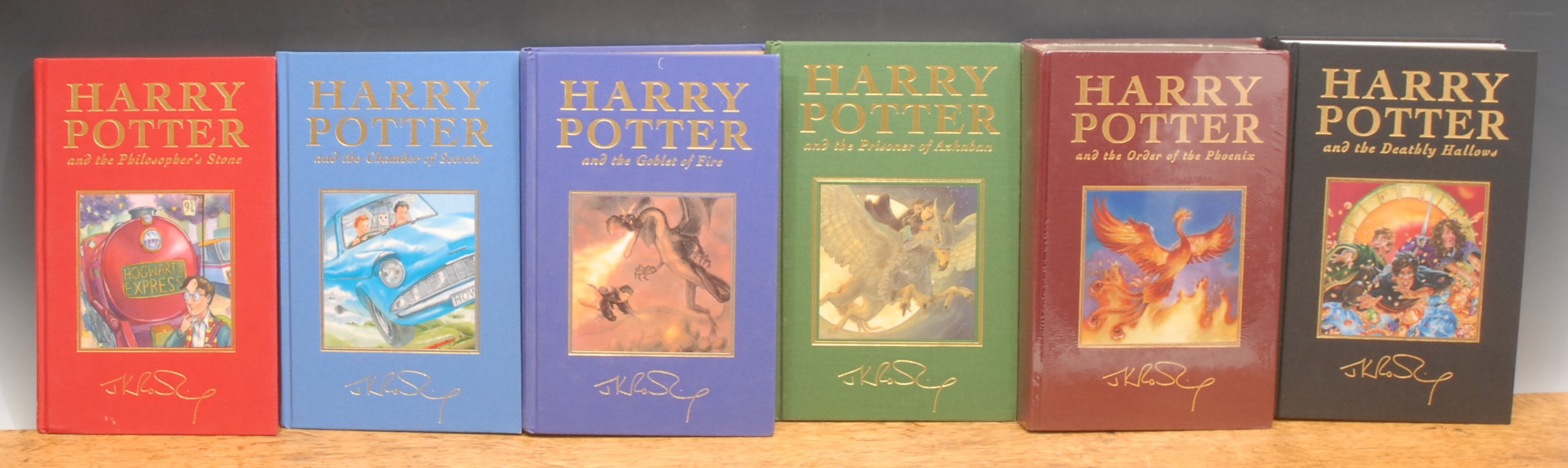Harry Potter – Bloomsbury 8vo de luxe editions withy page markers: Harry Potter and the Philosopher’s Stone (1999), red cloth gilt titles, author’s autograph and mounted illustration. 6 volumes out of seven so issued:  Harry Potter and the Chamber of Secrets (1999), blue cloth, gilt titles, author’s autograph and mounted illustration; Harry Potter and the Prisoner of Azkaban (1999), green cloth gilt titles, author’s autograph and mounted illustration; Harry Potter and the Goblet of Fire (2000), blue cloth, gilt titles, author’s autograph and mounted illustration; Harry Potter and the Deathly Hallows (2007), gilt titles, author’s autograph and mounted illustration; Harry Potter and the Order of the Phoenix (1st edn., 2003),brown cloth gilt titles, author’s autograph and mounted illustration, still in publisher’s shrink film as sold (6)