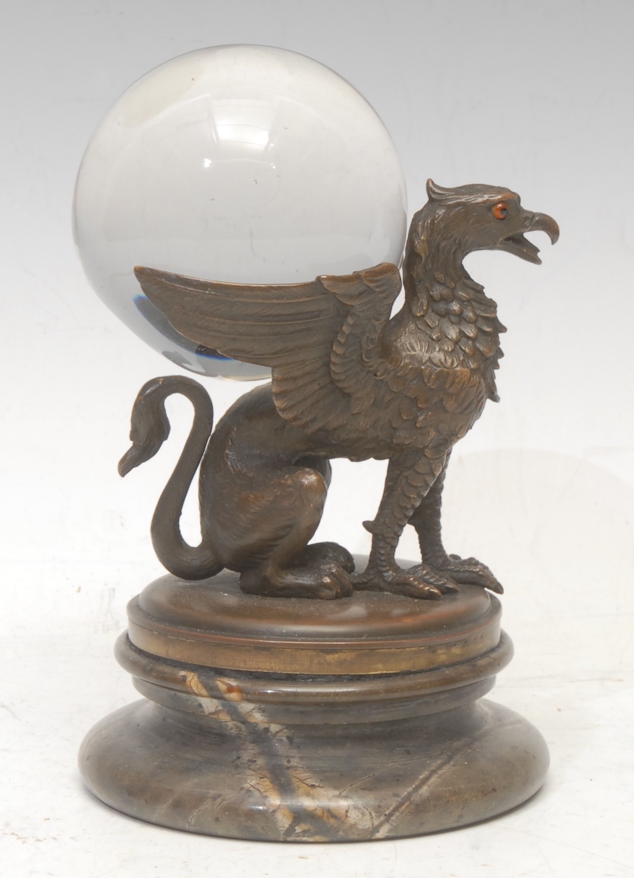 Mysticism and the Occult - a crystal ball, the early 20th century brown patinated bronze stand cast as a griffin, marble base, 16cm high overall