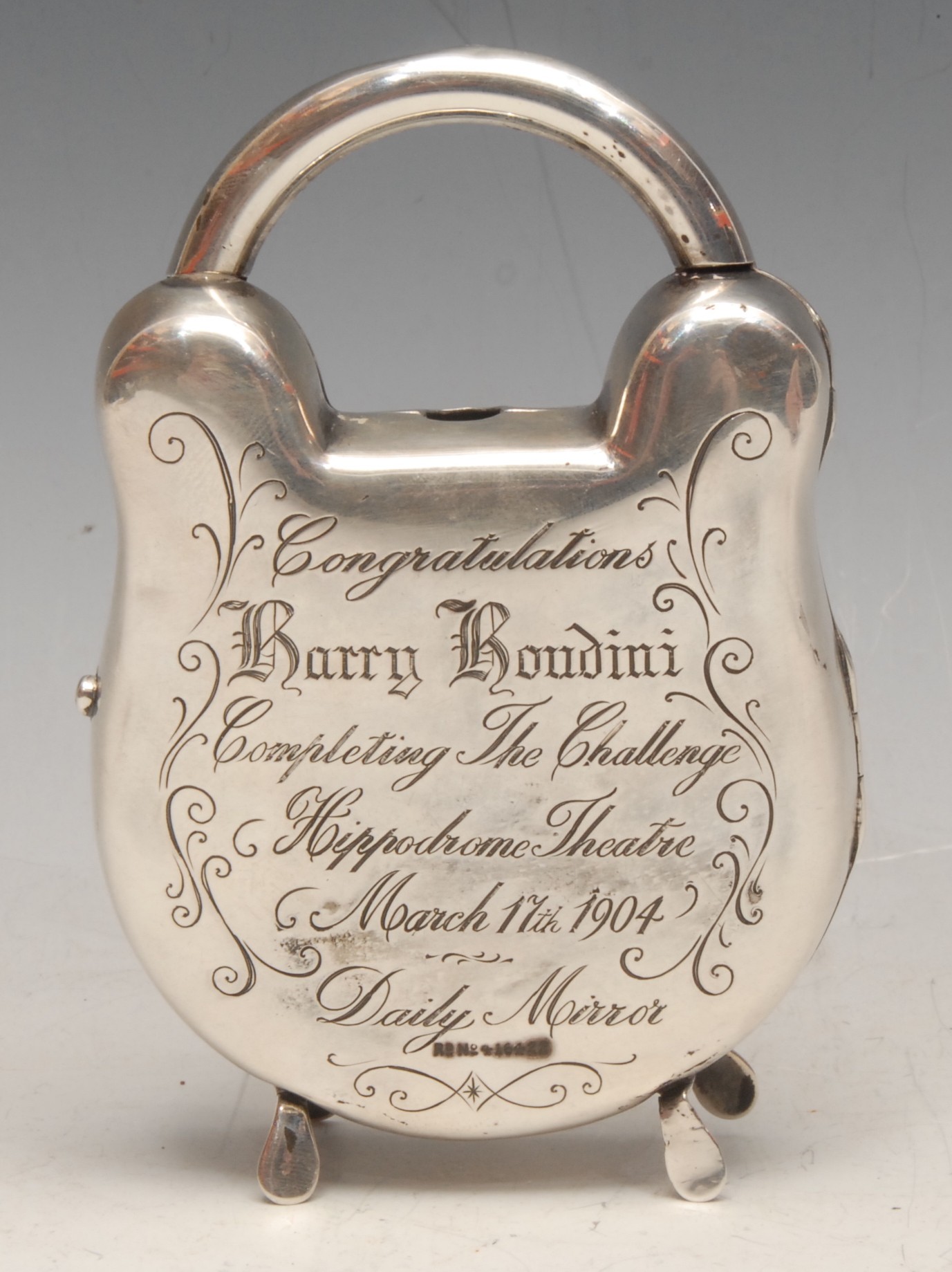 Magic, Conjuring & Escapology - an Edwardian silver novelty pocket watch stand, as a padlock, inscribed to verso Congratulations to Harry Houdini, Completing the Challenge, Hippodrome Theatre, March 17th 1904, Daily Mirror, hinged cover, 11.5cm high, London 1902  NB. The Daily Mirror challenged Houdini to escape from a specially made pair of handcuffs. The escape, referred to by Houdini as one of the most difficult of his career, took over an hour, with four thousand spectators in attendance. The escape has been the subject of much speculation.