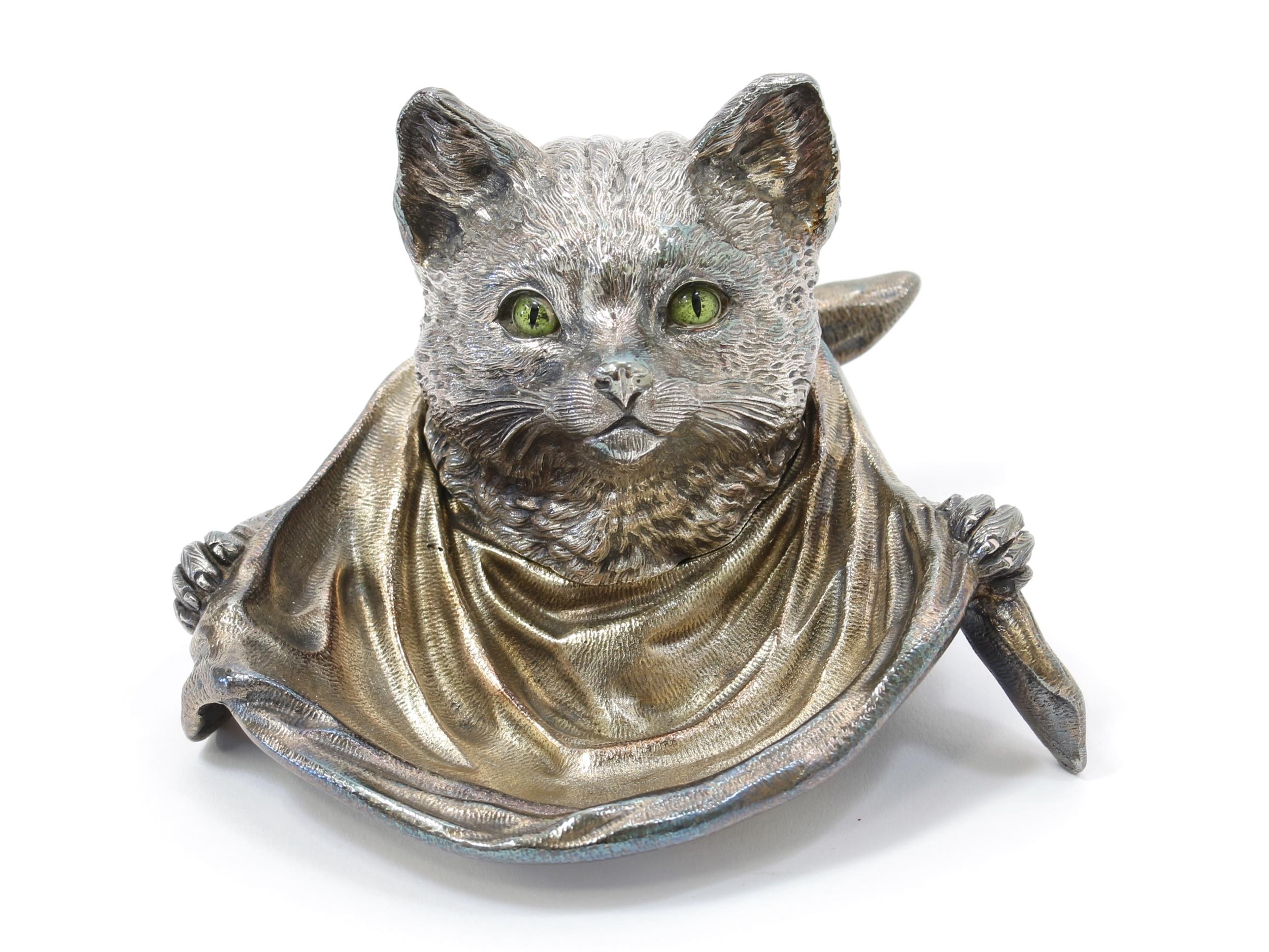 A silver plated novelty inkwell, as a cat wearing a bib, enamel eyes, hinged cover, 13.5cm wide