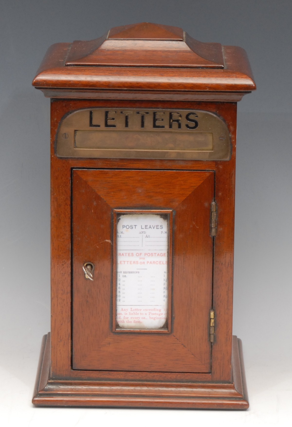 An Edwardian style mahogany novelty country house post box, pagoda top above a brass aperture inscribed Letters, and a rectangular door, centred by a glazed panel listing collection times, 32cm high