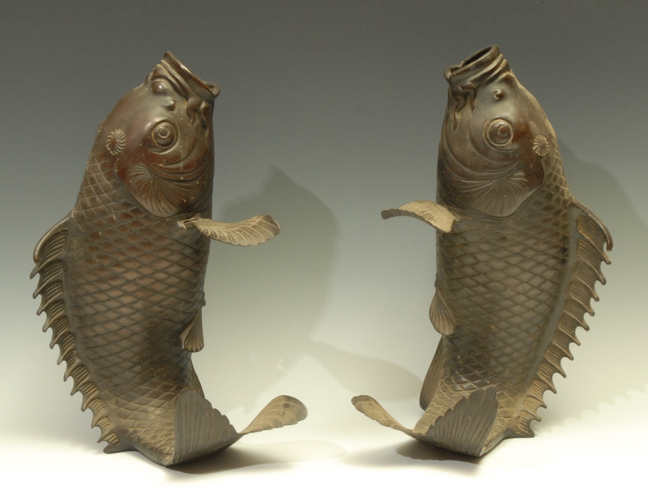 Japanese School, a pair of dark patinated bronze carp, modelled upright, detachable fins, 35cm high