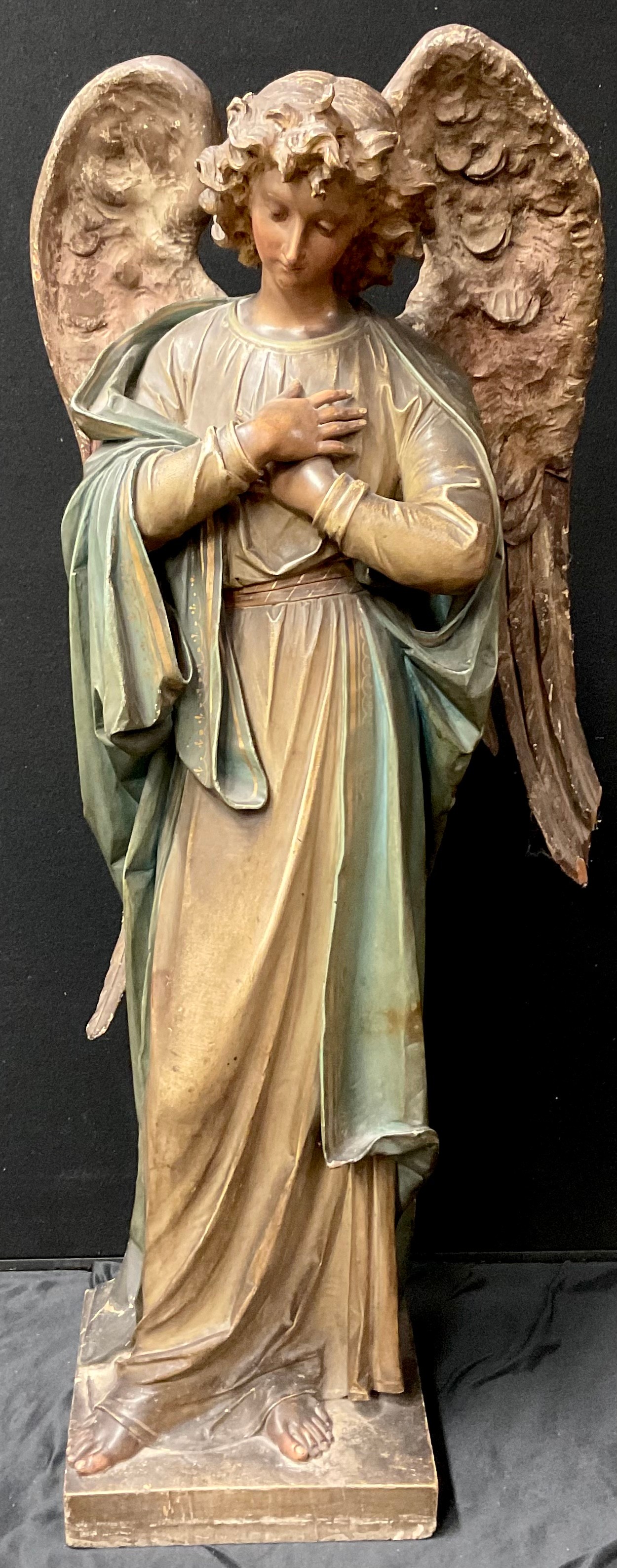 A large Continental softwood figure, carved as an angel, she stands, her hands crossed at her heart, square base, 97cm to top of head, 19th century