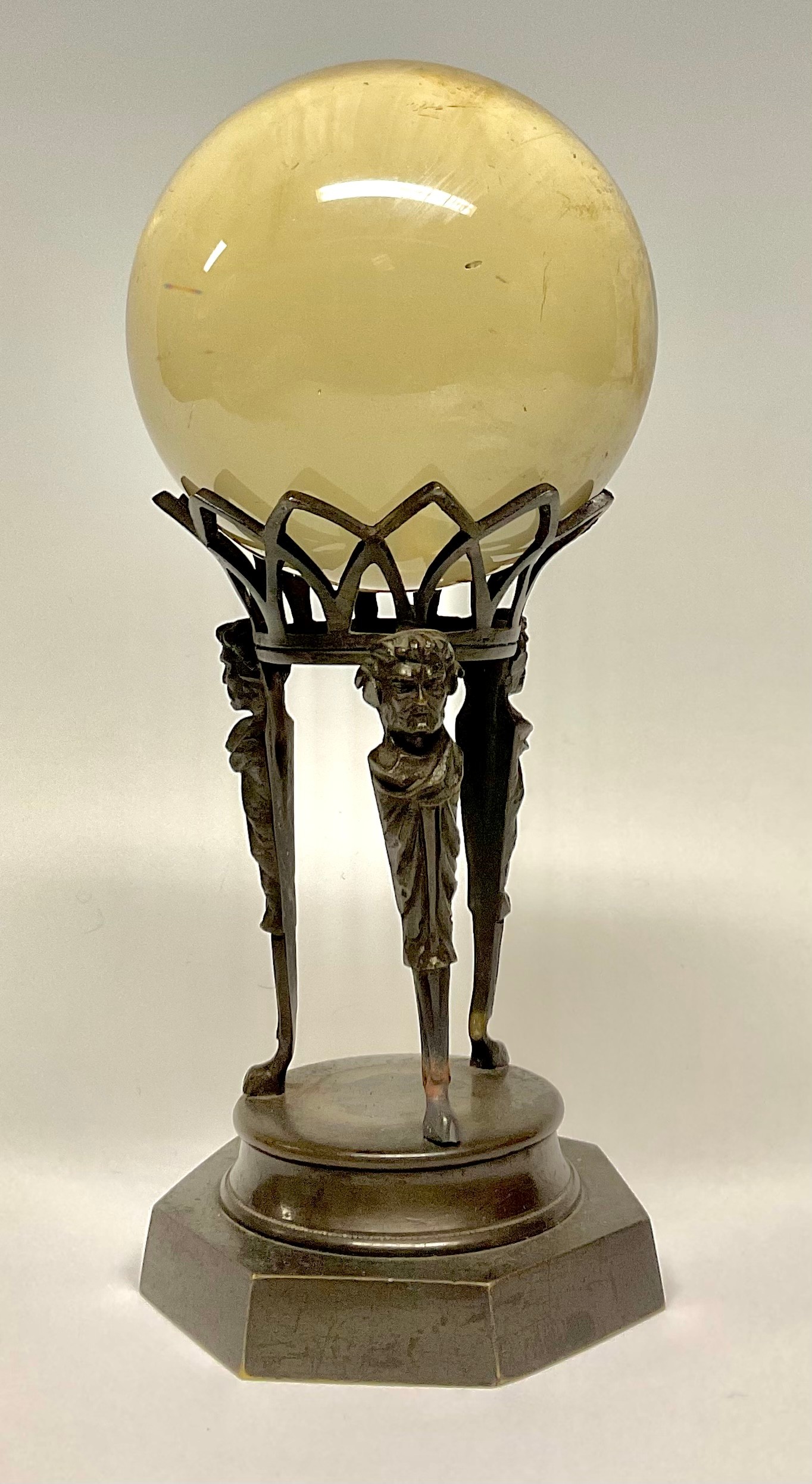 Mysticism and the Occult - a crystal ball, the Regency bronze stand with three satyr monopodia herms, heptagon base, 23cm high