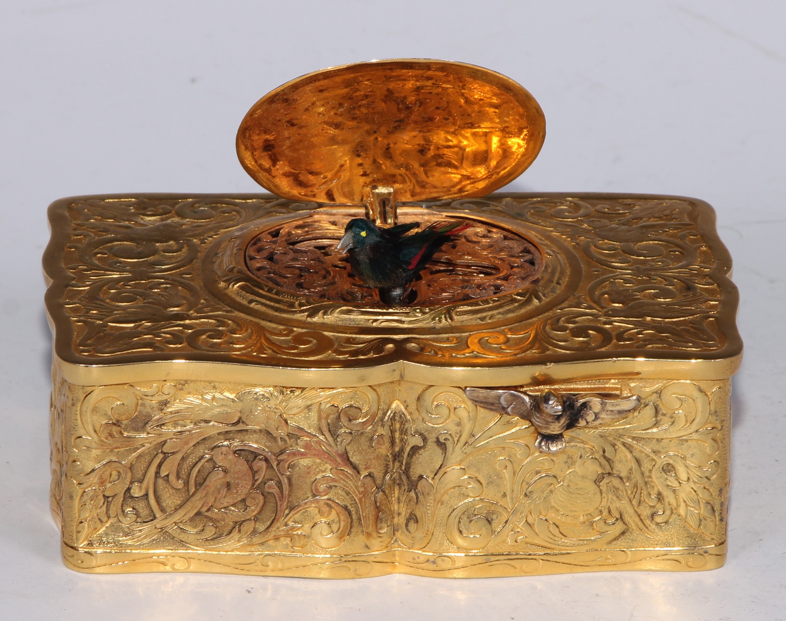 An early 20th silver-gilt singing bird automaton box, Swiss or German, possibly by Karl Griesbaum, in relief overall with leafy strapwork and avian subjects, 10.5cm wide, import marks for BCT Co Ltd, London 1930
