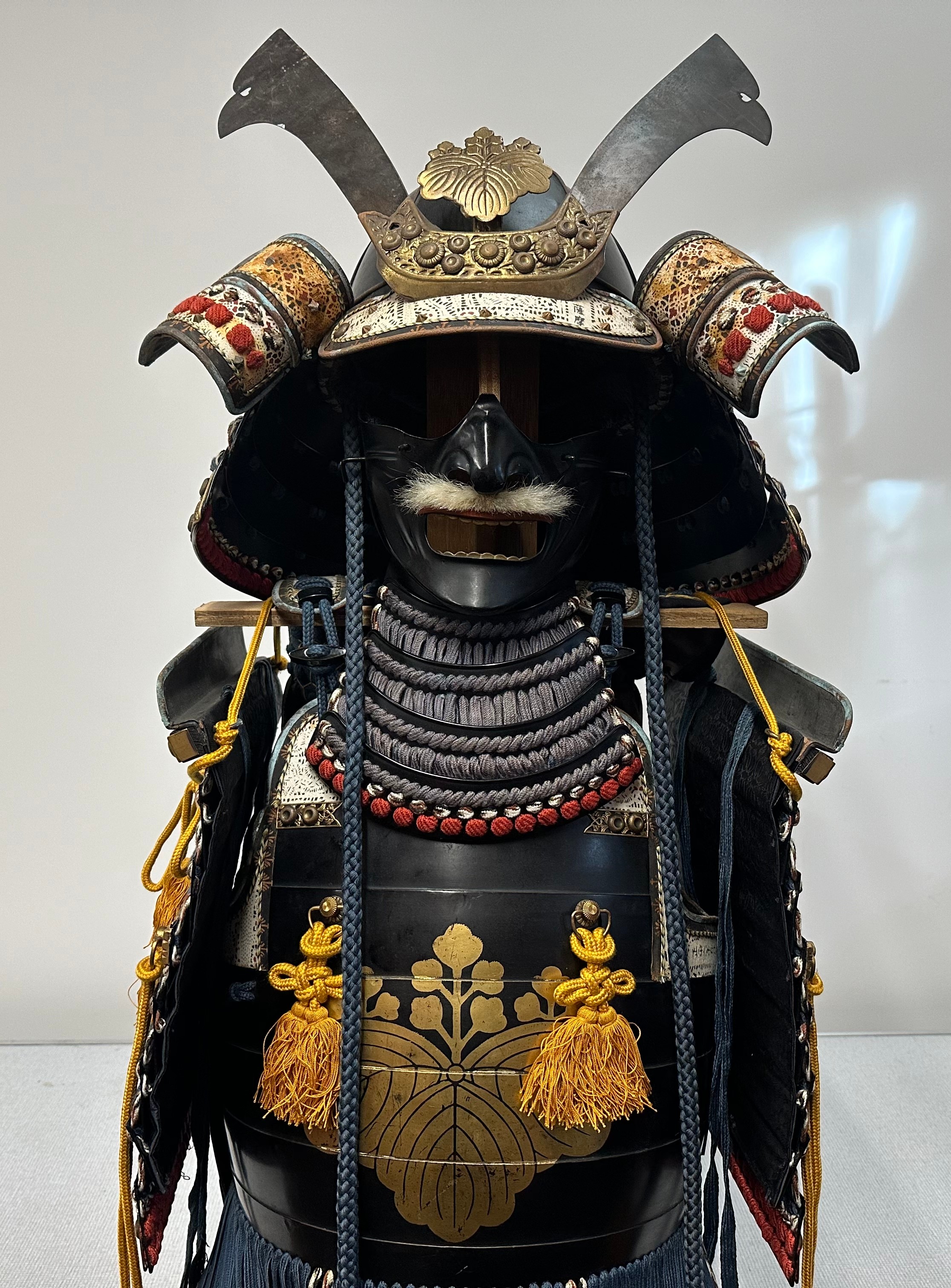 Suit of Japanese Samurai Armour. Complete with Kabuto Helmet with Maedate (Front decoration), Menpo face armour mask, Dō (cuirass), Sode (shoulder guards), Kusazuri (skirt of plates attached to the cuirass),  Kote (armored sleeves), Haidate (thigh protection),  Suneate (shin guards), plywood stand, etc all contained in a black transit box.