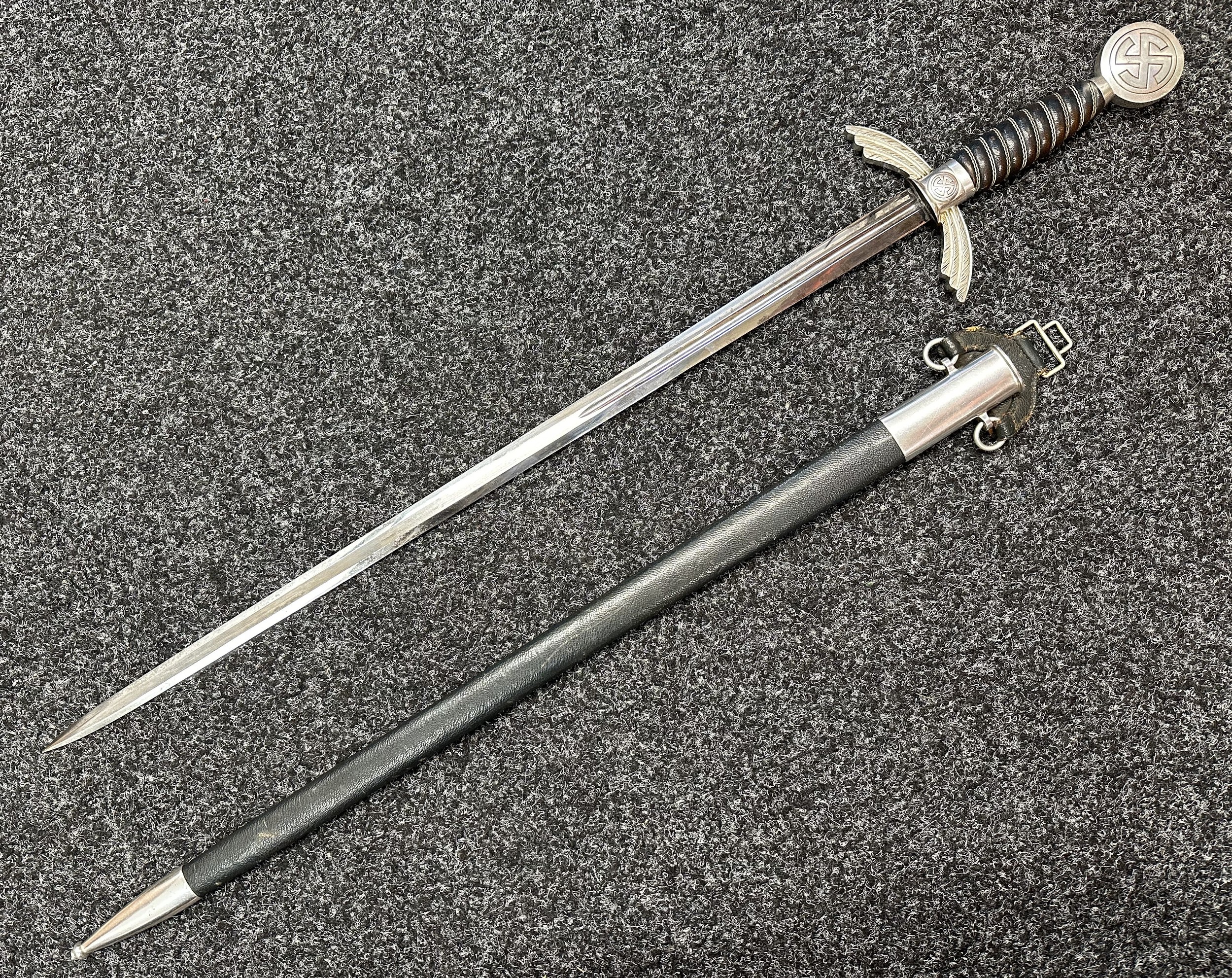 WW2 Third Reich Luftwaffe Officers Sword with double edged fullered blade 665mm in length, maker marked "SMF Solingen" along with Luftwaffe acceptance mark. Alluminium fittings, wire bound blue leather grip, pommel with Sunwheel Swastika. Overall length 850mm. Complete with blue leather covered scabbard with matching alluminium fittings and Sword hanger. New to the market, war souvenir of a British Serviceman.