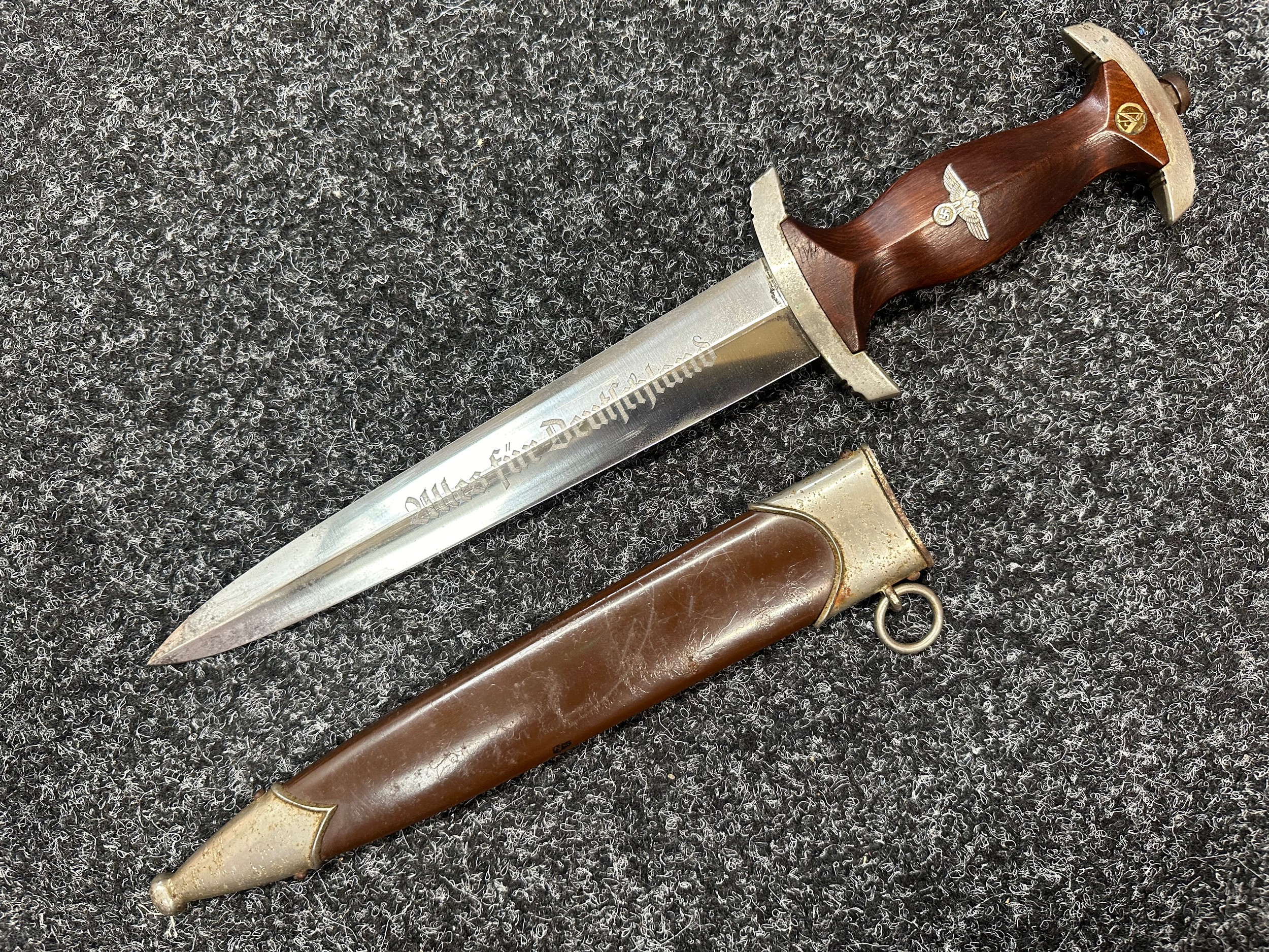 WW2 Third Reich SA Deinstdolch 1933 Pattern Dagger with double edged blade 221mm in length, etched motto "Alles Fur Deutschland" along with makers mark "RZM M7/13" (Artur Schüttelhöfer Solingen). Wooden grip inset the SA emblem and Eagle. Overall length 349mm. Complete with scabbard with original painted finish.