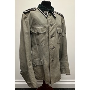 WW2 Rare Historically Significant Third Reich SS Totenkopfverbande privately custom tailored summer weight service tunic. Lightweight cotton material tailored in the style of a 1936 pattern tunic. Badge cloth faced collar with Totenkopf collar tab and rank tab for SS-Hauptscharführer. Shoulder straps piped in KZ Brown waffenfarbe. One rank pip missing for one strap. Sleeve eagle hand sewn with mothed wing tip. Tunic is very small size approx. 30 inch chest. No name or any markings. Sleeves are fully lined and the shoulders are padded. Part Rayon lining to shoulders. Underside of pocket flaps lined. Never had a cuff title. Provenance:  This item was obtain by a British Veteran of the 63rd Anti Tank Regiment Royal Artillery when his unit entered Bergen-Belsen Concentration Camp in April 1945.  Scanned photo shows the British Veteran wearing the tunic back home in Mansfield, Nottinghamshire in 1945. New to the market.