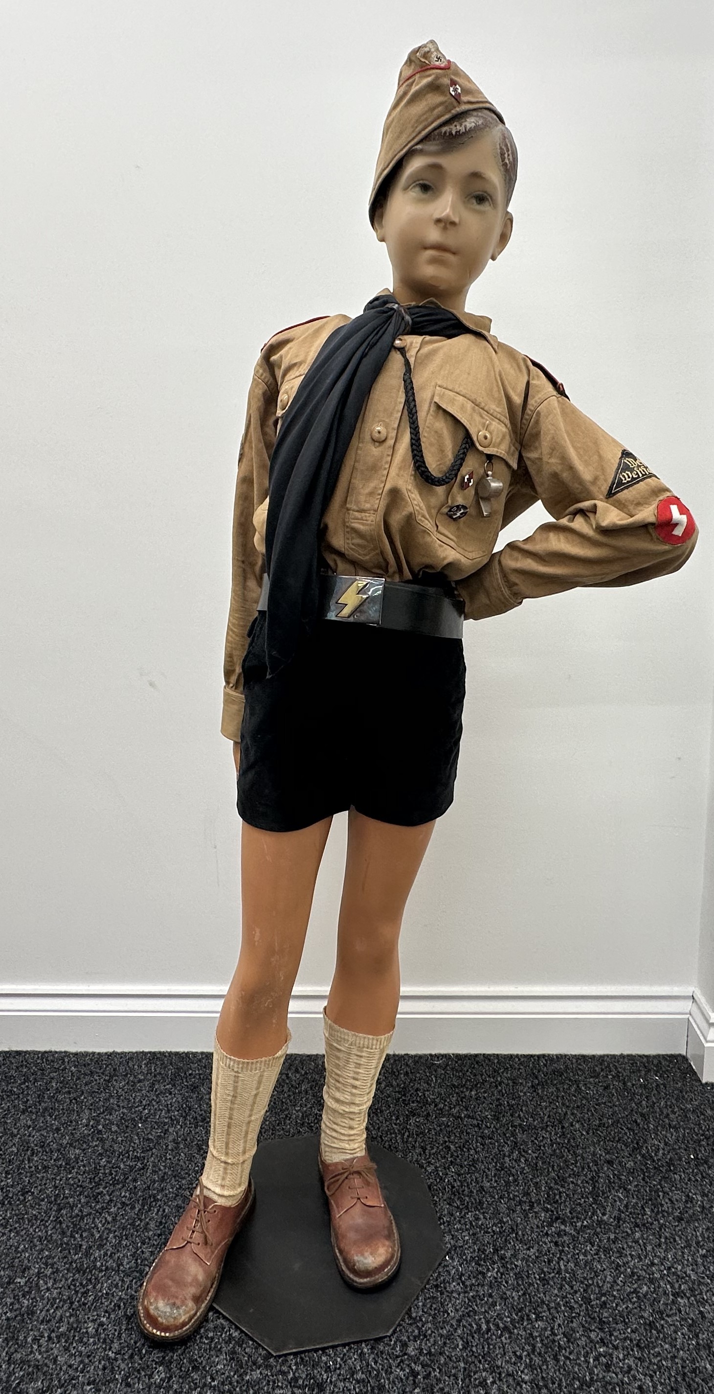 WW2 Third Reich Deutche Jungvolk Mannequin comprising of: vintage mannequin: HJ Summer cap with RZM paper label, size 58: Brown shirt with full insignia, shoulder straps, area triangle for West Westfalen, DJ Rune, Glider Qualification badge, : Belgian made black corduroy shorts: SS marked whistle on black lanyard: HJ enamel membership badge RZM marked: DJ Shooting award RZM marked: DJ Belt and buckle, both unmarked. (Neckerchief and leather woggle are modern). Socks and shoes.