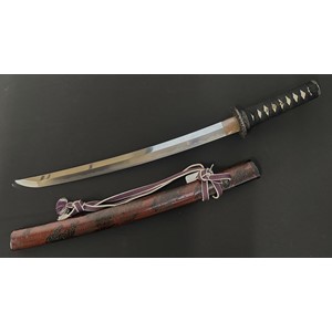 Japanese Wakizashi Sword with single edged blade 445mm in length. Good Hamon line. Signed tang. Overall length 610mm. Complete with red/black lacquered wooden saya which contains a signed Kozuka knife which is additionally maked on the blade. Has a previous Mallams Auction lot label from 2017.