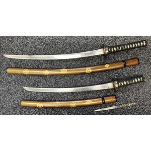 Japanese Pair Daisho Swords with complete with display stand and cloth protective bags. Larger Katana sword with single edged blade 540mm in length with Hamon line to edge, tang is not signed, ray skin grip with Menuki present, overall length 760mm. Complete with Laquered wooden Saya with gilt Mon decoration: smaller Wakizashi sword with single edged 470mm long blade with Hamon line, unsigned tang, Tsuba matches the other sword, ray skin grip with menuki, overall length 624mm. Complete with laquered wooden Saya complete with knife with signed single edged blade 120mm in length, overall length 216mm.  (2)