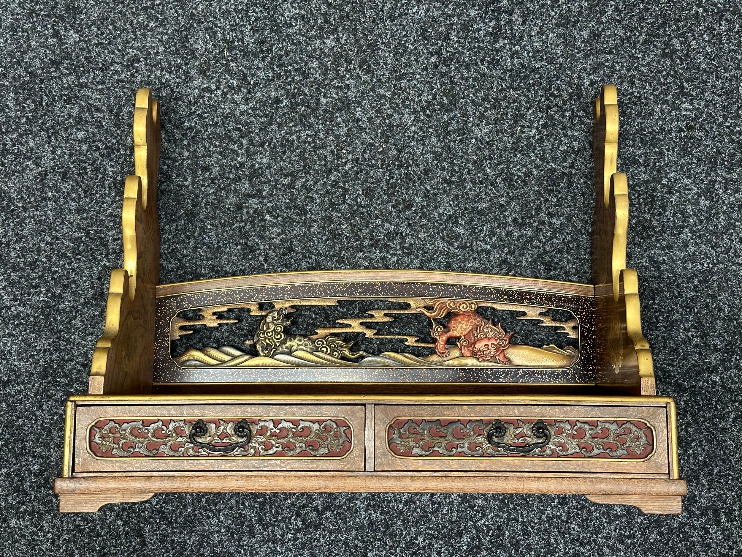 Japanese Sword Display Stand for three swords. Wooden construction with decorative brass inlays. Two drawers. Width 49cm, height 38cm, depth 22cm.