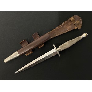 WW2 British 2nd Pattern Fairbairn-Sykes Fighting Knife. Early Nickle finish knife with 169mm long blade. Crossguard is marked with a WD Broad Arrow & 5. Hand chequered grip. Overall length 297mm. Complete with early pattern scabbard with nickle finished chape. Both tabs to scabbard are present. Retaining elastic has split: New to the market with provenance. Original owner was Harry Holmes, Royal Engineers. Harry missed D-Day having picked up an injury playing football for his Regt. He  later fought in Normandy and North West Europe where he carried the knife.