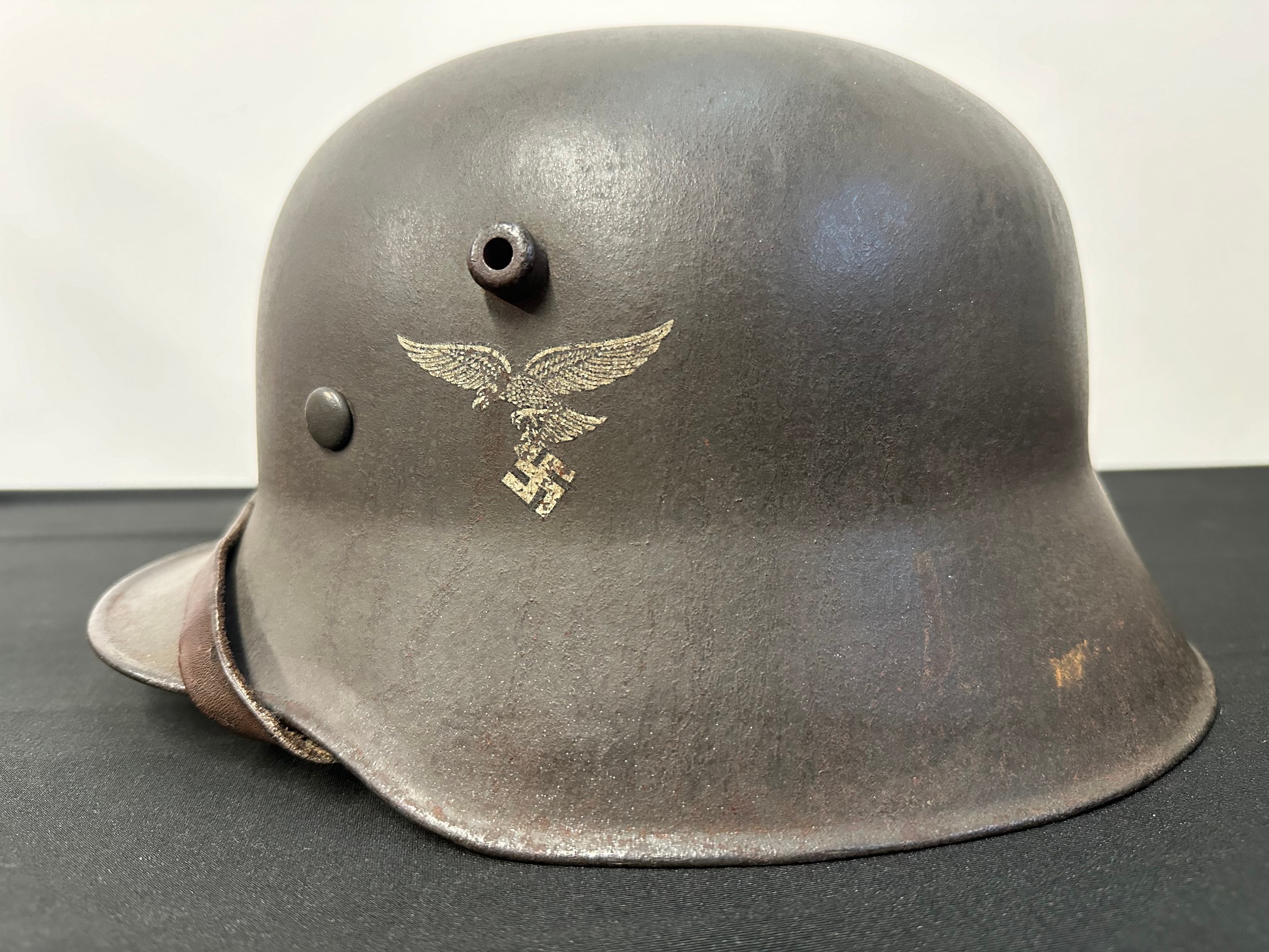 WW2 Third Reich M16 Steel Helmet, maker and size marked "N66" along with batch number "E446" to crown. Transitional period helmet fitted with early pattern M35 alloy liner band with square bales, leather liner and chinstrap. Note: Luftwaffe early pattern droop tail eagle and National colours decals are not original.