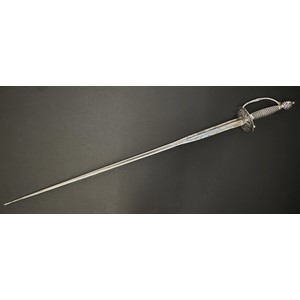 Small Sword with incurved triangular section blade 810mm in length. No makers marks. Silver peirced cirular guard with piled arms decoration and clamshells. Cross guard and D shaped guard decorated again with arms motifs. Wire bound grip. Peirced round pommel with piled arms decoration. Overall length 980mm. No scabbard.