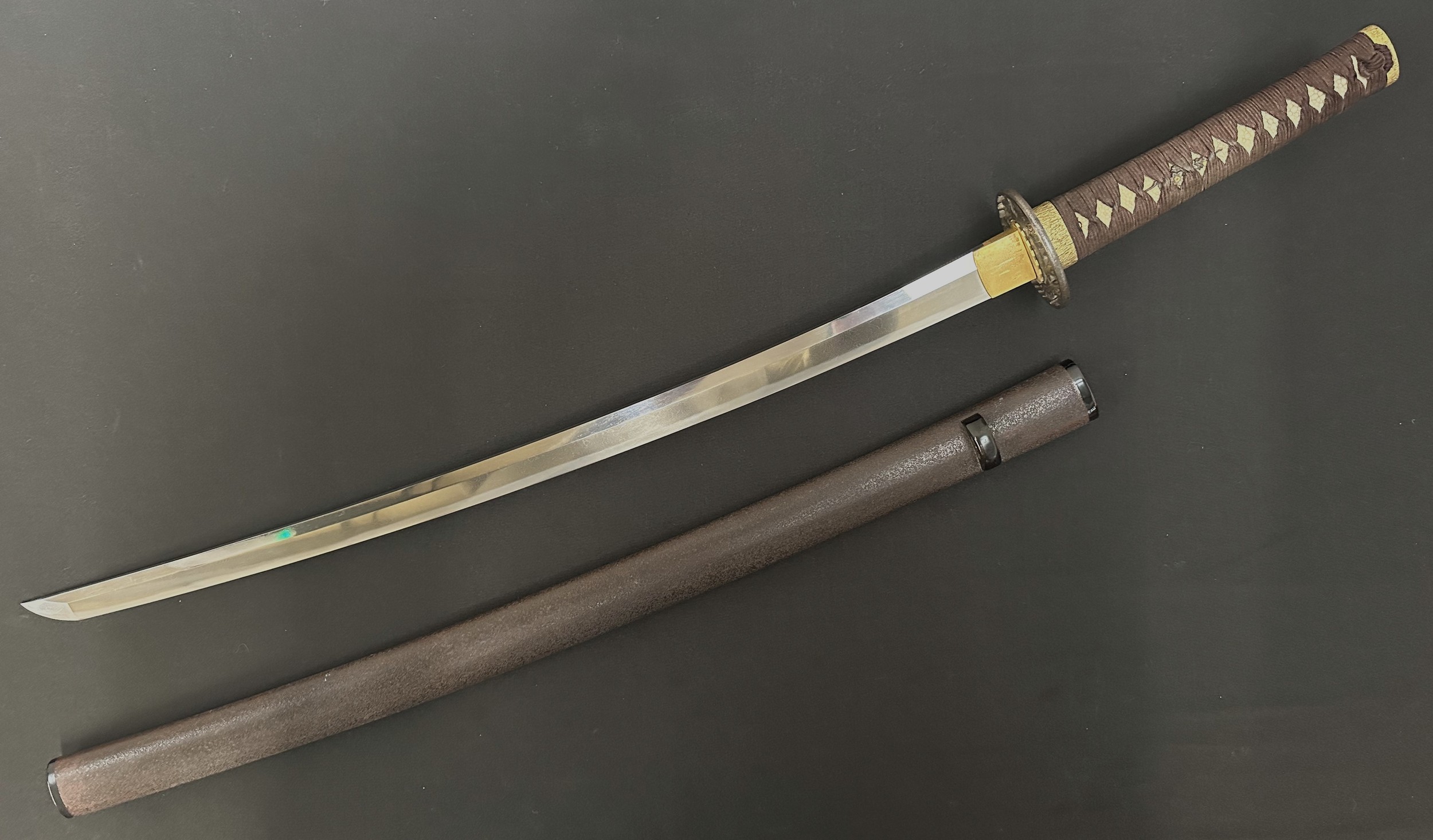Japanese Kan'ei era Wakizashi Sword circa 1624-1644. The sword is complete with a NTHK Shinsa 2003 Certification done at the Euro-Group Token Kai and was classed as "Kanteisho - 75 points - Important". Single edged blade 620mm in length with very good Suguha (Straight) hamon line. Two holes to tang. Unsigned. Iron Tsuba, unsigned. Samegawa Shagreen Ray Skin grip with brown Tsuka-ito cloth binding with Menuki to both sides. Overall length 845mm. Brown lacquer finish to the Saya scabbard.