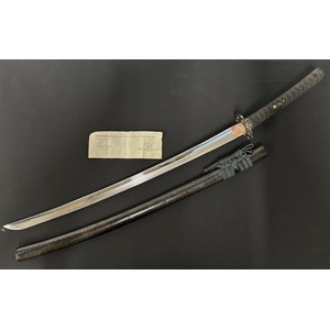 Japanese Katana Sword with single edged blade with very good Hamon line 676mm in length. Two holes to the unsigned tang. Copper Habaki. Black Tsuba with gilt floral decoration, unsigned.  Samegawa Shagreen Black Ray Skin grip with black Tsuka-ito cloth binding with Menuki to both sides. Overall length 930mm. Complete with Saya with black & gilt lacquer decoration and dark blue Sageo hanging cord. Comes complete with a WW2 British Capture paper.