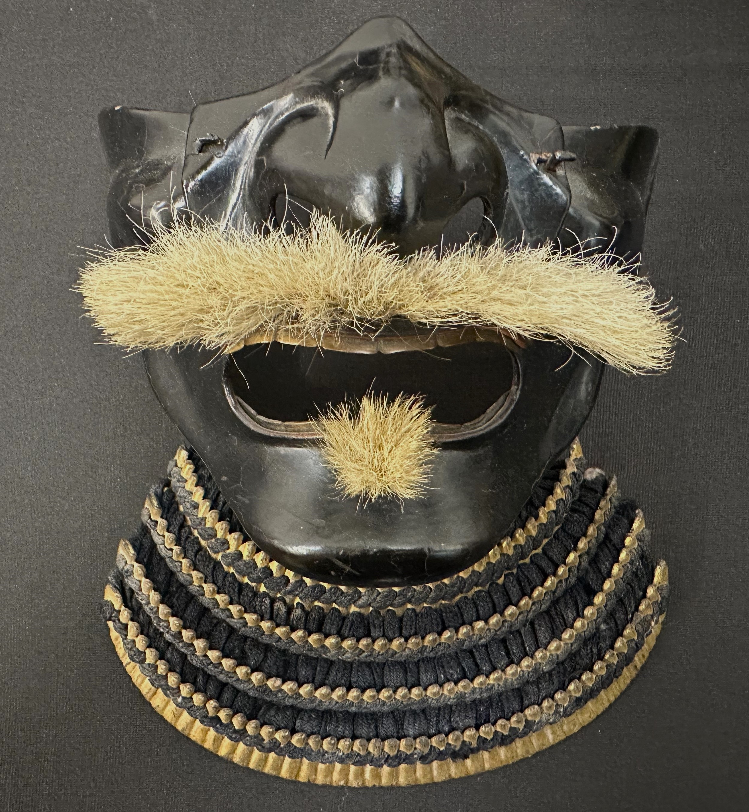Japanese Samurai Menpo or Me no shita Facial Armour. Black laquered finish with gilt decoration and hair moustache. Multi part construction.  Shikoro neck guard. No markings.