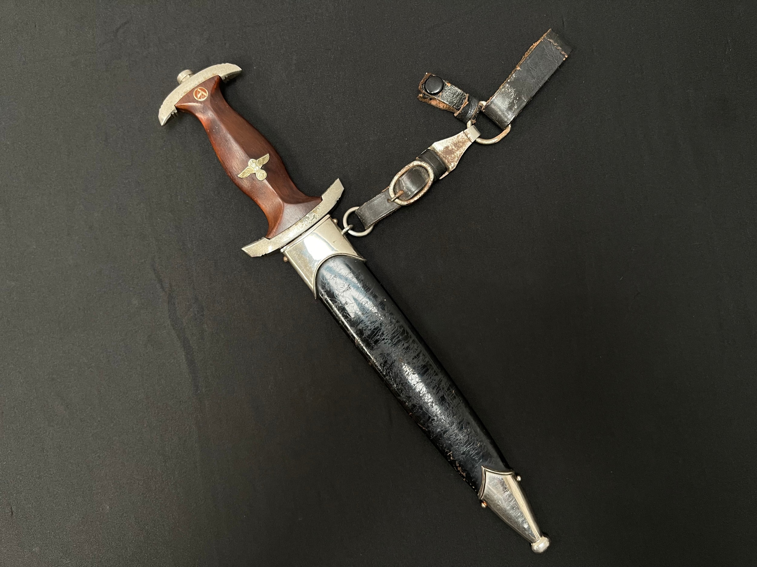 WW2 Third Reich NSKK Dienstdolch M1933 pattern dagger with double edged blade 220mm in length with "Alles fur Deutchland" etched motto and maker marked "RZM M7/103". (Josef Hack, Hackwerke GmbH, Steyr, Osterreich.) Overall length 350mm. Complete with black painted NSKK scabbard which is also complete with the scarce three part leather hanger which is maker marked "RZM M5/ 71 plus makers logo "olc" for  Overhoff & Cie, Lüdenscheid.