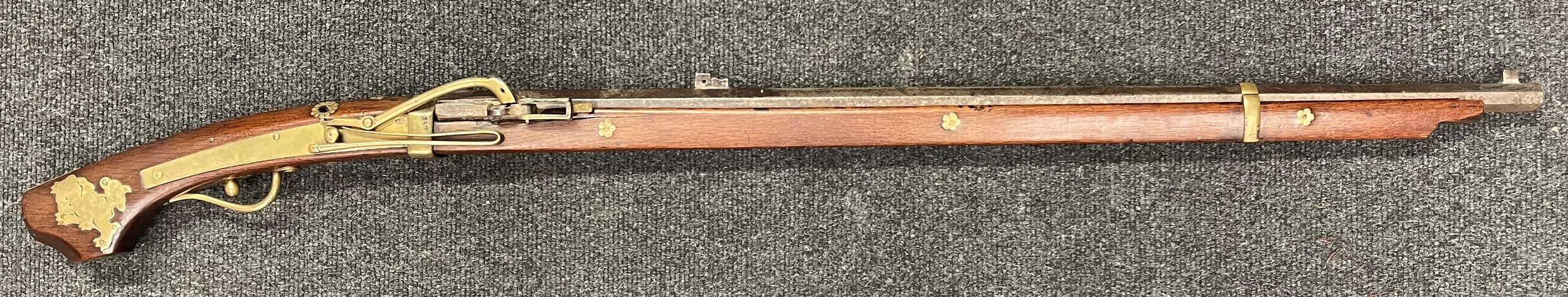 Japanese Samurai Matchlock Musket with decorated octagonal barrel 767mm in length. Bore approx. 12mm. Decorated with Swallows in flight. Brass barrel band. Working action. Brass lock, trigger guard and cherry blossom stock decoration along with brass Shisa dog (Fu lion) to butt. Japanese markings to lock and to brass plate on butt. Overall length 107cm. No ramrod. Section 58 (2) No licence required in the UK.