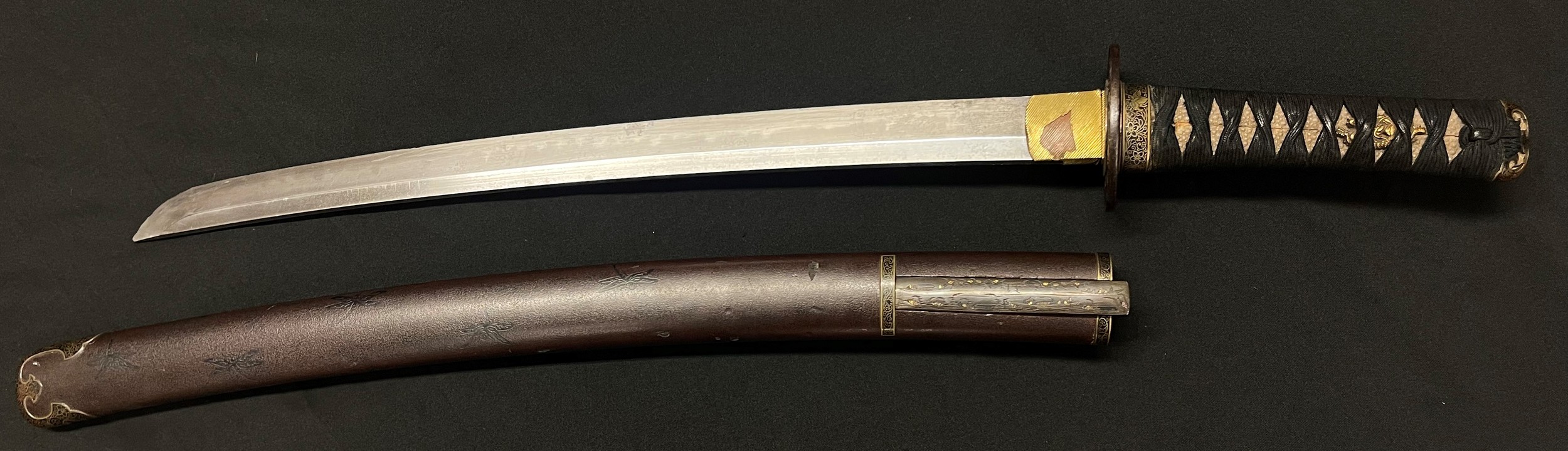 Japanese Wakizashi Short Sword with single edged blade 455mm in length. Hamon line is present. Signed tang. Tsuba with floral decoration. Grip with Menuki. Overall length 620mm. Saya scabbard decorated with Dragonflies along with Kogatana knife with 95mm long blade, bronze decorated grip, signed, overall length 193mm. Also with Kogai hair pins in brass with decoration.