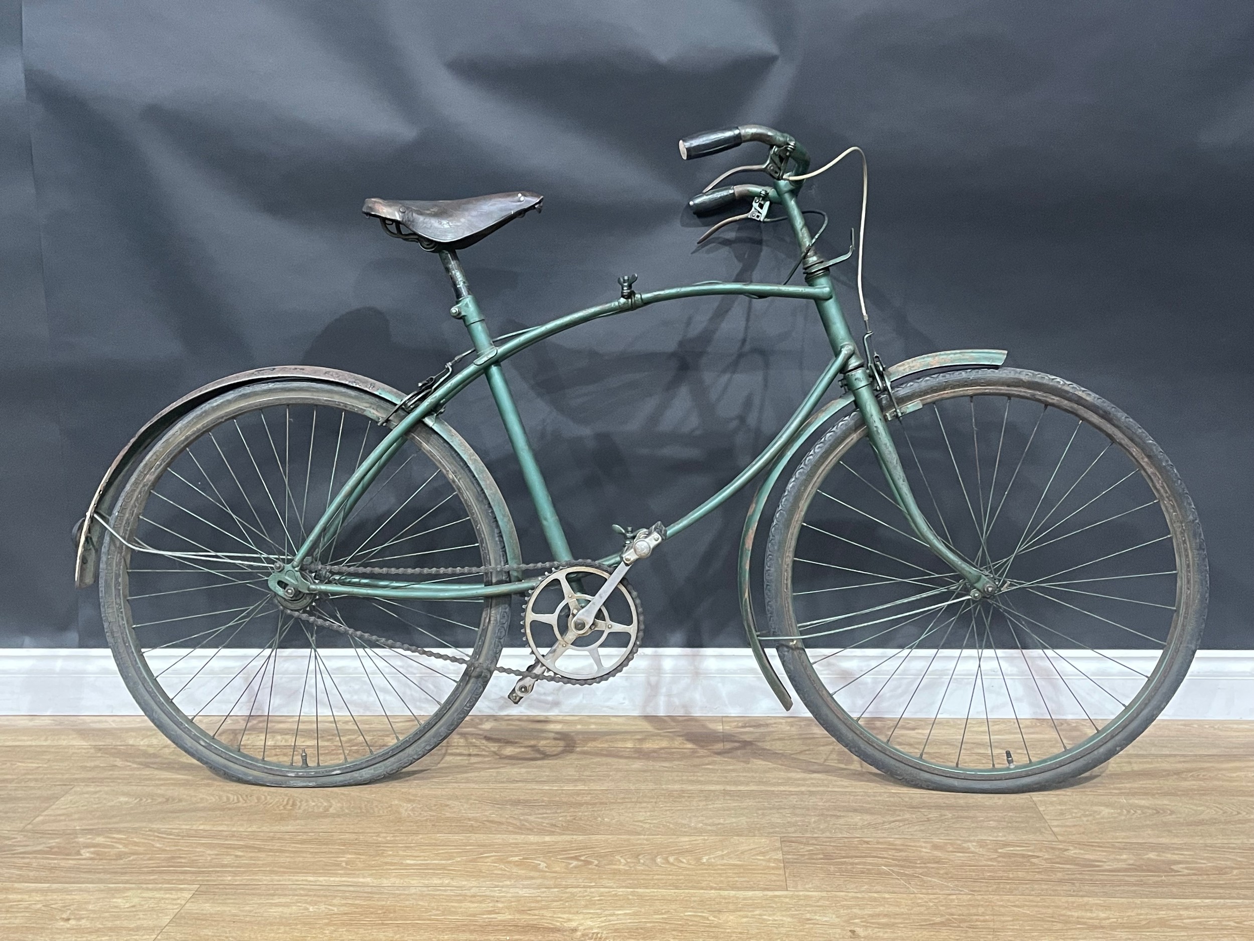WW2 British BSA Paratroopers Folding Bicycle. Original unrestored condition. Frame number R49229. The bike retains it's original BSA leather seat, original BSA Handlebar grips, BSA Lamp bracket, correct pattern brakes to both front and rear, both correct brake levers along with both "War Grade" tyres. Post war it has been fitted with mudguards to front and rear along with new sproket and conventional pedals. Postwar green paint. Only 70,000 Parabikes were produced during the war.