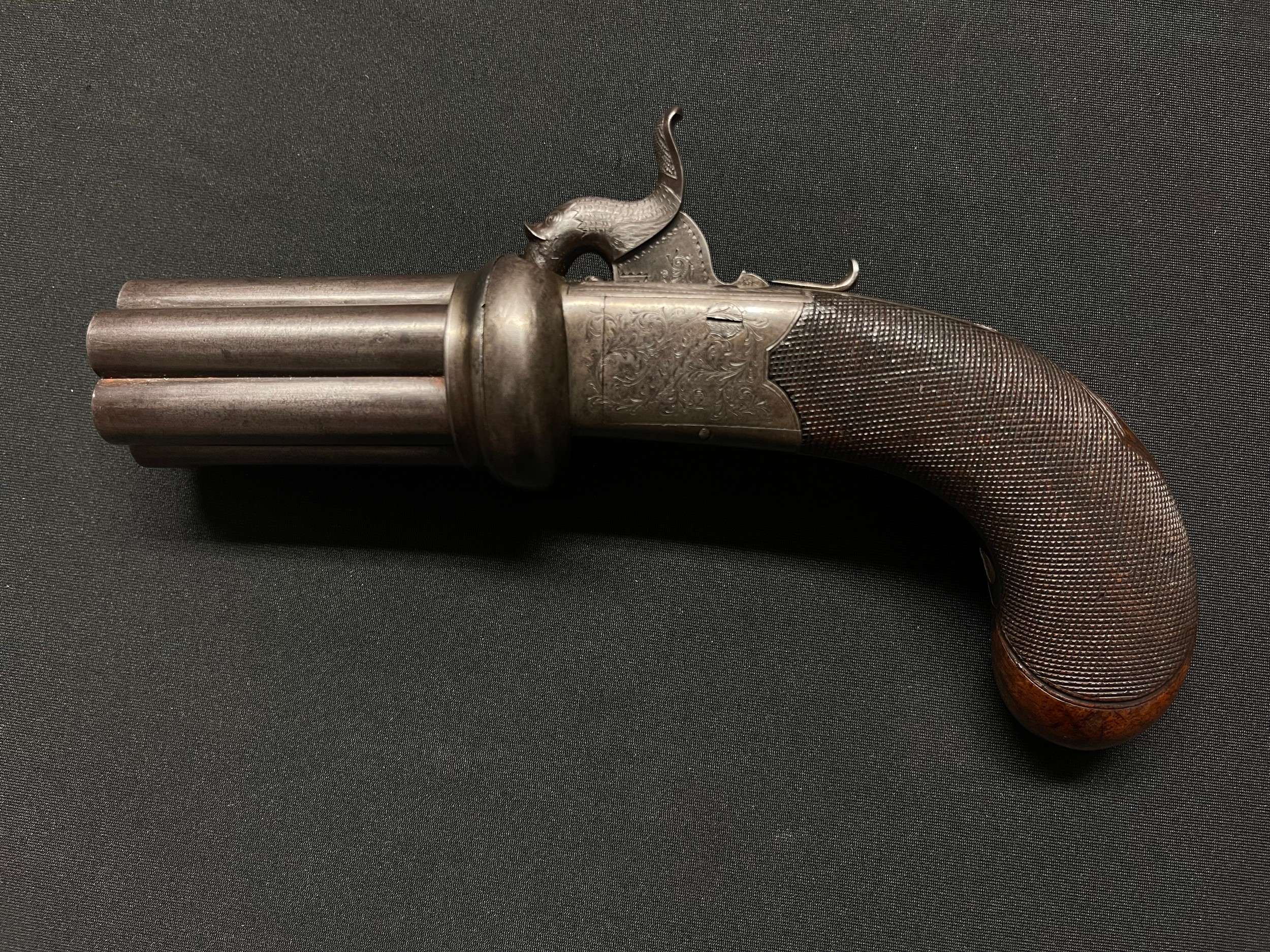 English Pepperbox Pistol with 6 barrels each 65mm in length, bore approx. 9mm by "Cort & Co, Leicester". Working action and safety catch.  Folding trigger. Plain white metal escutcheon plate. Engraved decoration to both sides of the lock and to the Dolphin shaped hammer. Overall length 205mm. NOTE: Section 58 (2) No licence required in the UK.
