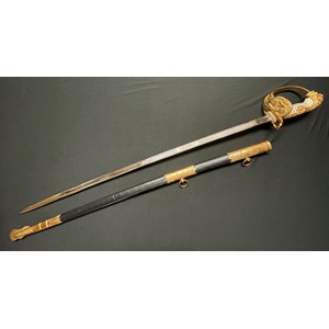 Kreigsmarine Officers Lion Head Sword with pipe backed blade 810mm in length with etched decoration of sailing ships, foliage and anchor to one side, the other side having foliage, sailing ship and naval trophy with trident to centre. Blade has makers trade mark of "E & F Horster Solingen". Fine white celluloid grip retaining the original wire binding. Gilt folding guard with central anchor, guard with fine relief, leading to the lion head pommel having set with green and red (port and starboard) jewelled eyes. Ferrule in the form of a band of oak leaves. Plain folding rear catch. Overall length 950mm. Complete with leather and brass mounted scabbard with two suspension rings