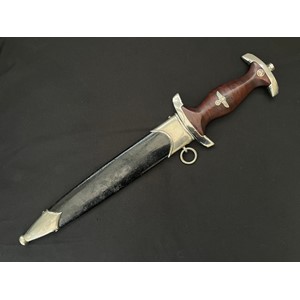 WW2 Third Reich NSKK 1933 Pattern dagger with double edged blade 224mm in length with etched "Alles fur Deutschland" motto and scarce makers mark for "Gebr. Becker, Solingen". Crossguard SA Gruppe marked "Wf" for Westfalen. Overall length 346mm. Tiger stripped grain to wooden grip complete with original insignia. Complete with black painted scabbard.