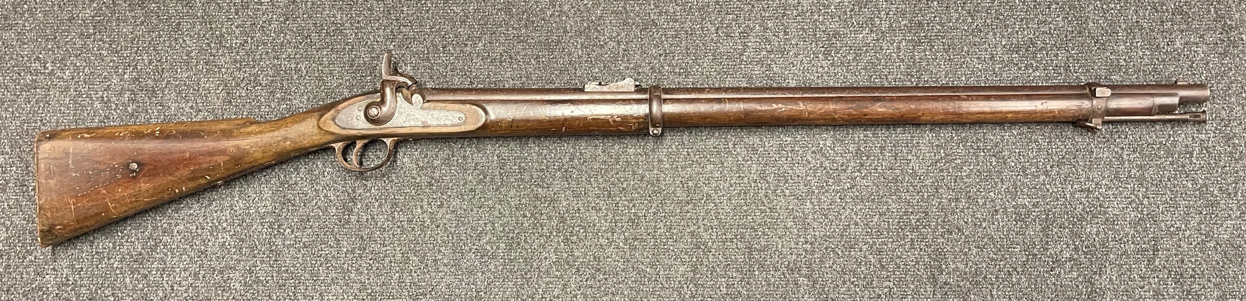 British Military "Bar on Band" Enfield Short Percussion Cap Rifle. Working action. 83cm long barrel. Lock marked 1860 and Tower with Crown VR. Barrel with British military proof marks. Stock with Board of Ordnance roundel. Overall length 124cm. Production did not commence until 1859 and it was soon superseded  the Pattern 1860 short rifle, only a few thousand of the "bar on band" variants were produced. A scarce British military service rifle with low production figures and a very limited service life. NOTE: Section 58 (2) No licence required in the UK.