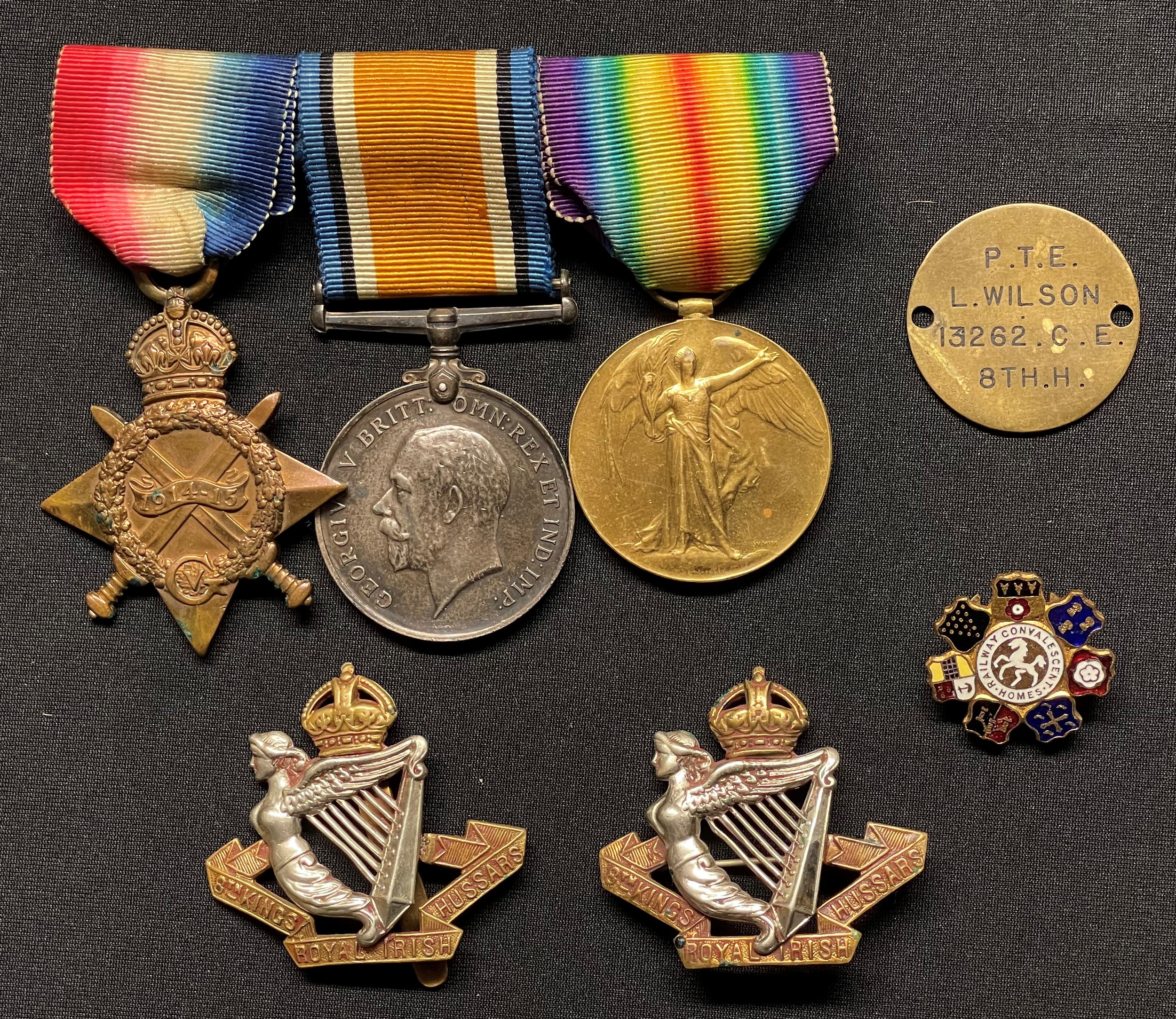 WW1 British Medal group comprising of 1914-15 Star, British War Medal and Victory Medal to 13262 Pte L Wilson, 8th Kings Royal Irish Hussars on bar with original ribbons. Along with two cap badges (one brooch pinned) and an enamel Railway Convalescent Homes lapel badge.