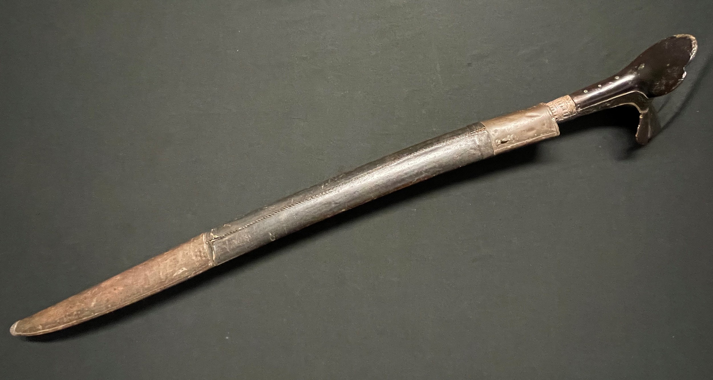 Turkish Ear Sword with single edged blade 590mm in length with engraved Islamic decoration and lettering. White metal mounts to blade which continue onto the horn grip. Overall length 722mm. Complete with leather covered wooden scabbard.