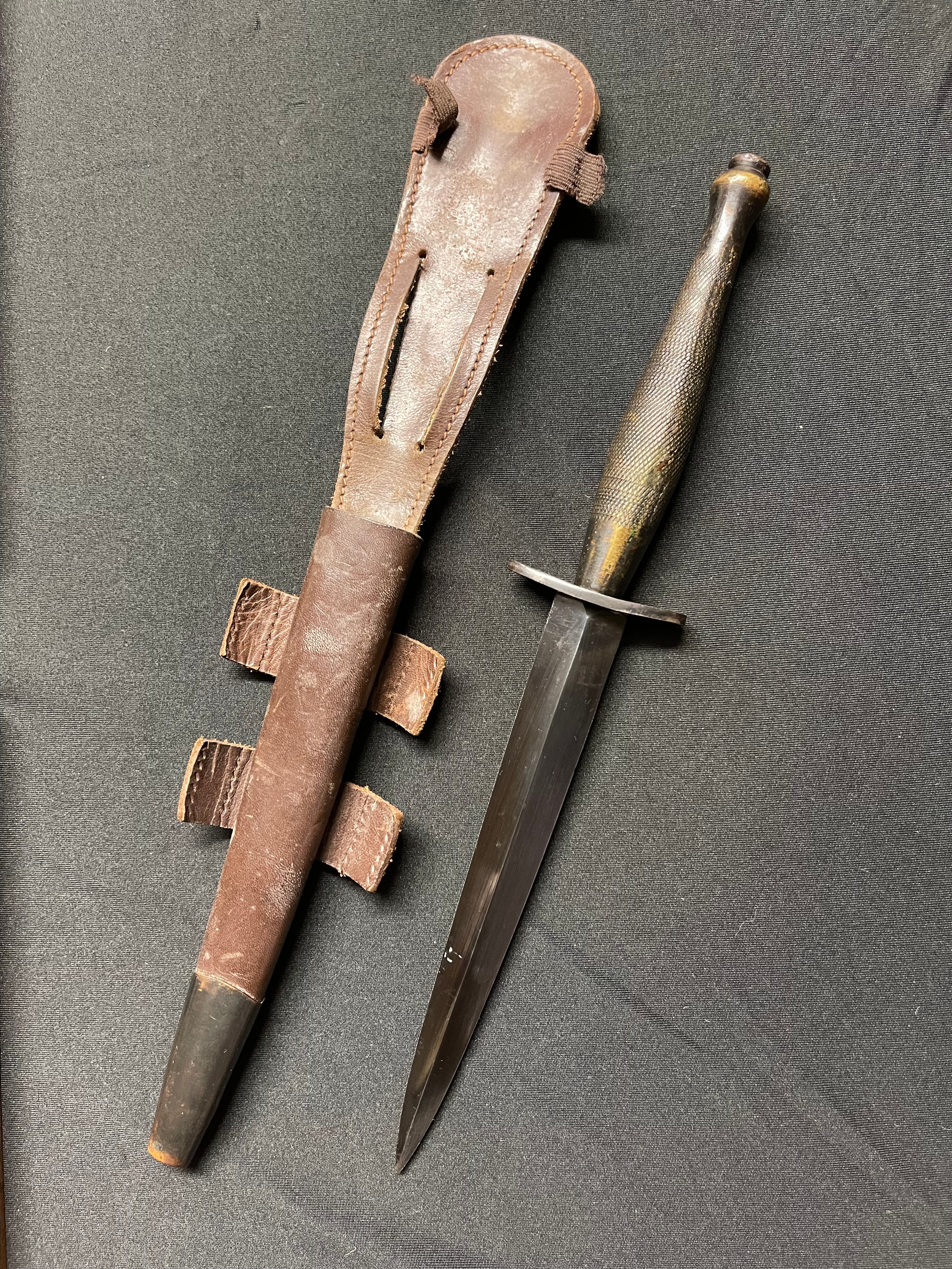 WW2 British 2nd Pattern Fairbairn Sykes fighting knife, maker marked on crossguard with WD Broad Arrow and B. Double edged blued blade 165mm in length. Overall length 290mm. Complete with scabbard. Scabbard retaining elastic loop a/f.