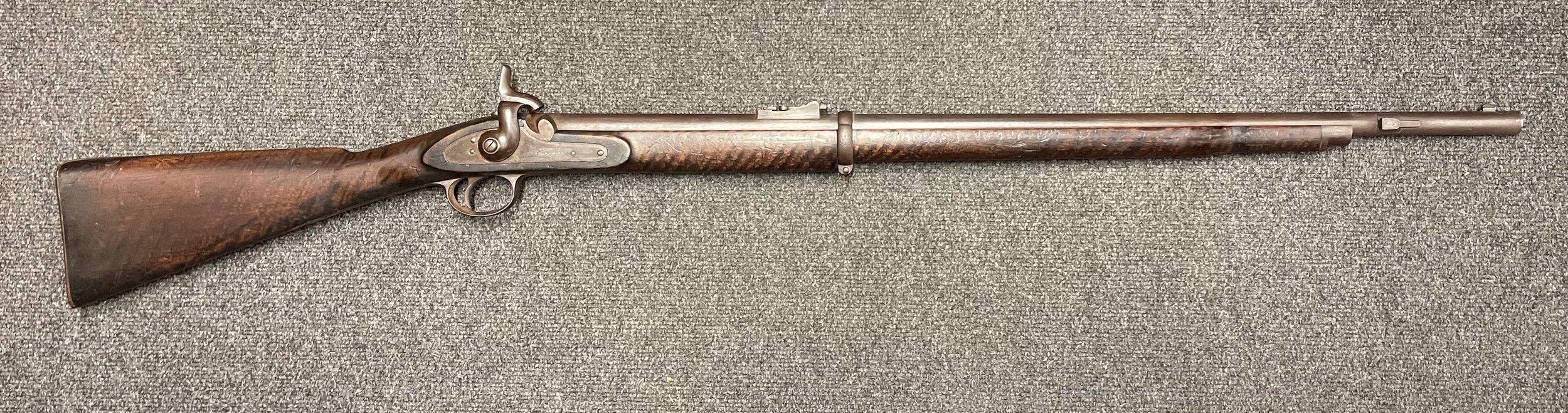 A Volunteer two band Enfield "bar on barrel"  Percussion Cap short rifle, the lock stamped "Conway Manchester". 83cm long barrel. Overall length 124cm. Working action. Missing Nipple. The stock with "tiger stripe" pattern. No ramrod. NOTE: Section 58 (2) No licence required in the UK.