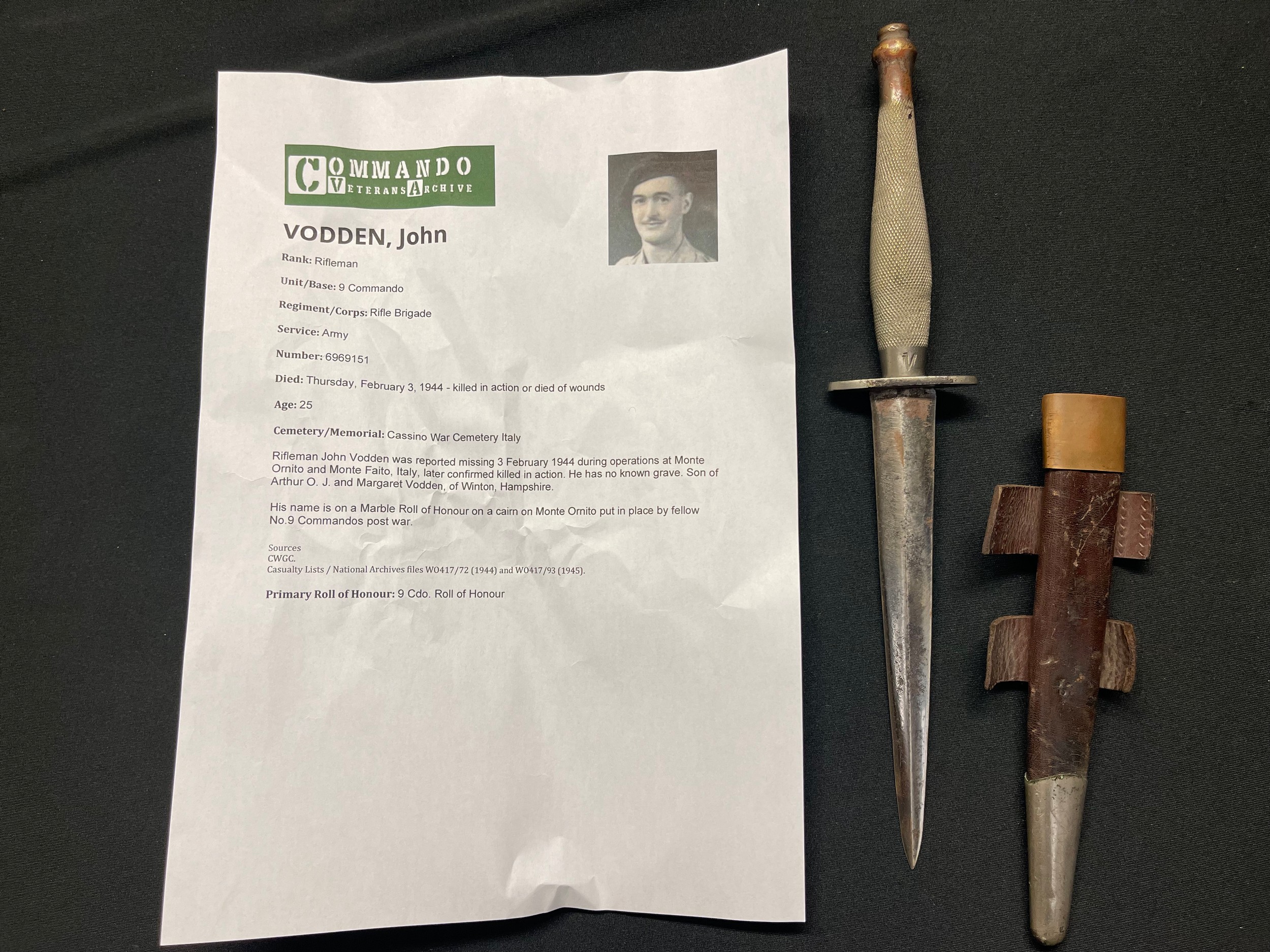 WW2 British all nickel second pattern Fairbairn Sykes Fighting Knife. The guard marked. /|\56 and the initials "J.V." to the grip. Housed in its leather scabbard with nickel chape. Faint soldiers number to the rear. Attributed to John Vodden, Rifle Brigade and 9th Commando