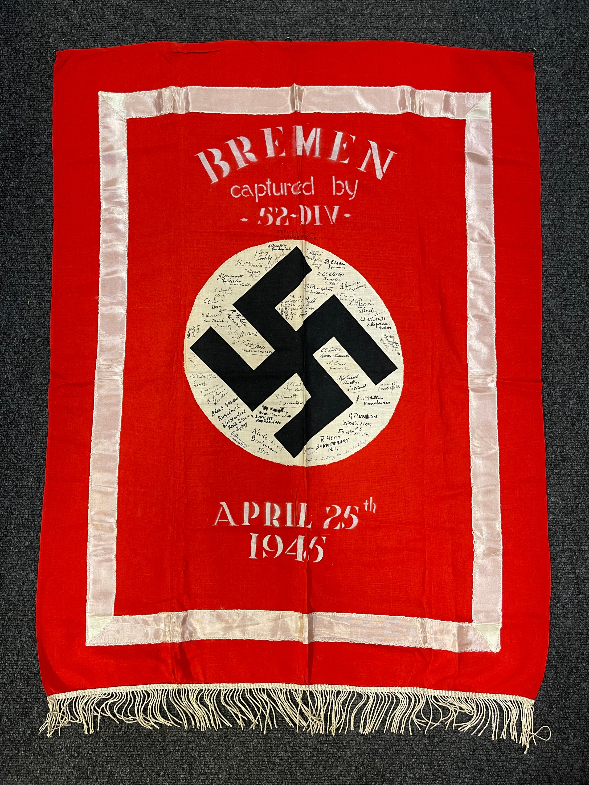 WW2 Third Reich Podium Banner captured by members of the British 52nd Lowland Dvision on April 25th 1945 in Bremen. The banner has been stenciled with the place and date and then signed by individual members of the unit. Size 103cm x 74cm. Three hanging rings. Never been in a collection before and was brought home as a souvenir by the vendors Great Uncle Stan Burford who also signed the banner. A photo of him in uniform on his BSA M20 motorcycle can be emailed to the winning bidder.