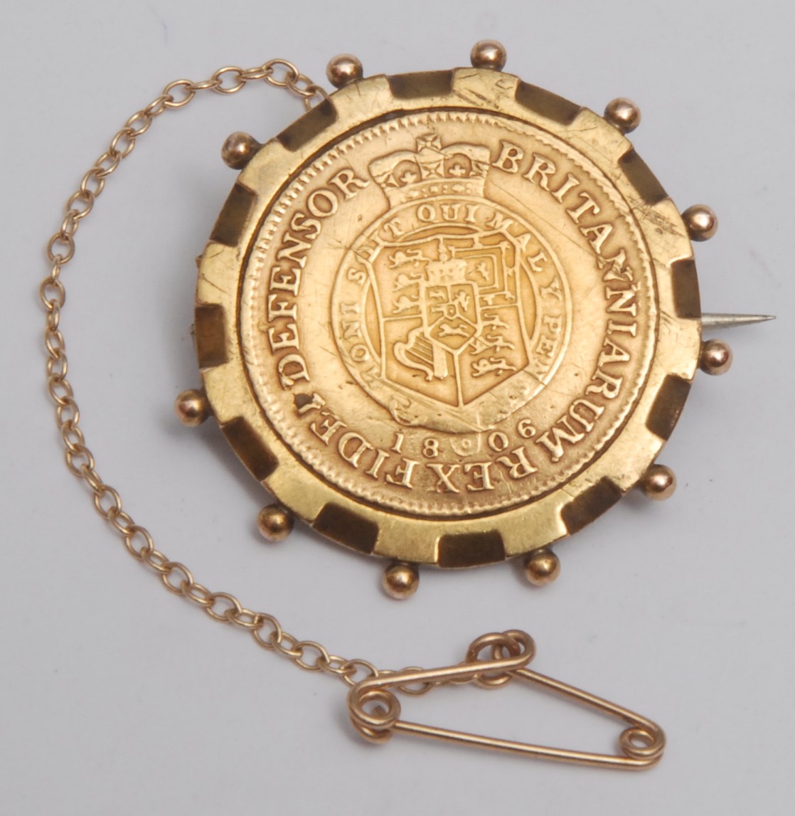 A George III 1806 half guinea, (garter type) gold coin, later mounted as a brooch, 2.6cm overall diameter, yellow metal mount (tested as 9ct gold) 7.8g gross