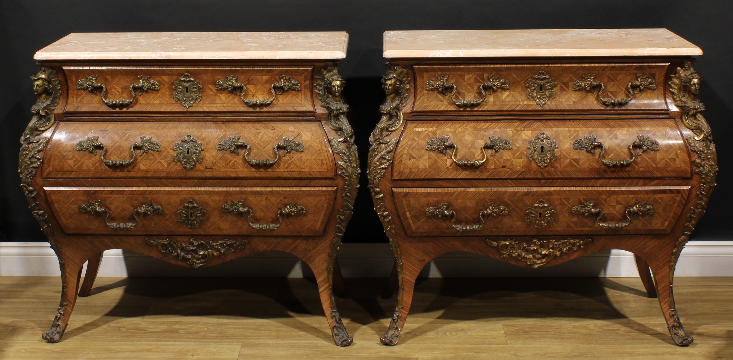 A pair of French Louis XV Revival gilt metal mounted parquet de versailles commodes, each with marble top above three long drawers, the mounts cast as male and female herms, the handle mounts and escutcheons cast as fruiting vine, 87cm high, 98cm wide, 47.5cm deep, late 19th/early 20th century
