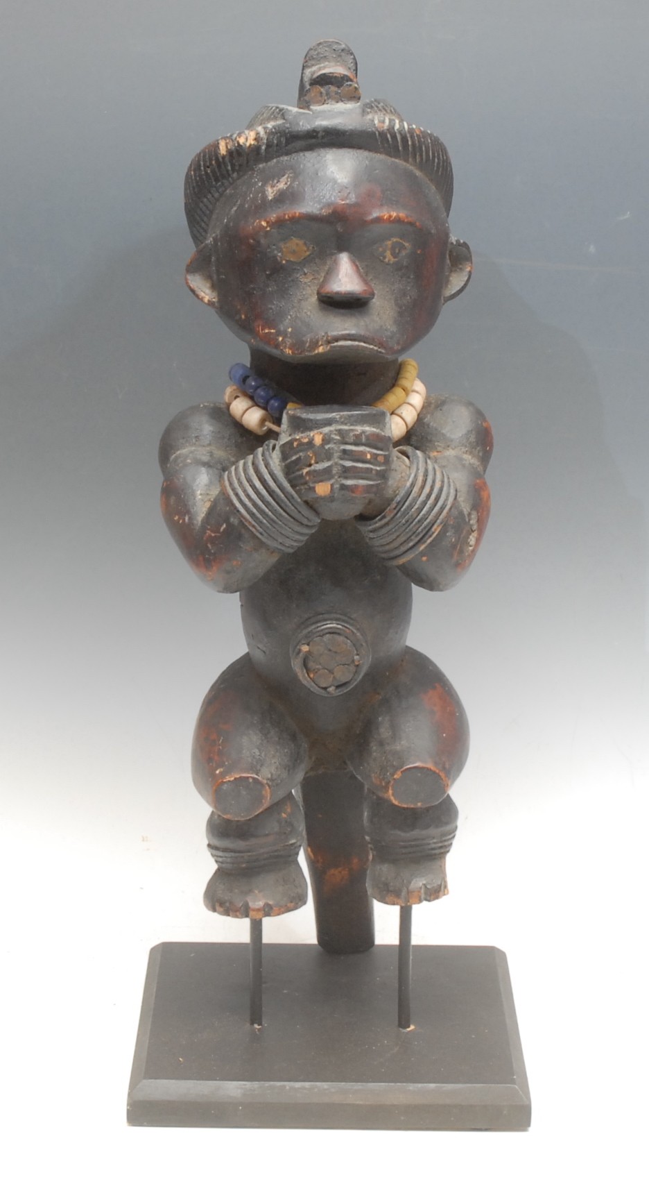 Tribal Art - a Fang Byeri figure, Ntumu, depicted crouched, holding a vessel, adorned with beadwork necklaces, 47cm high, collector's display plinth, Gabon/Cameroon